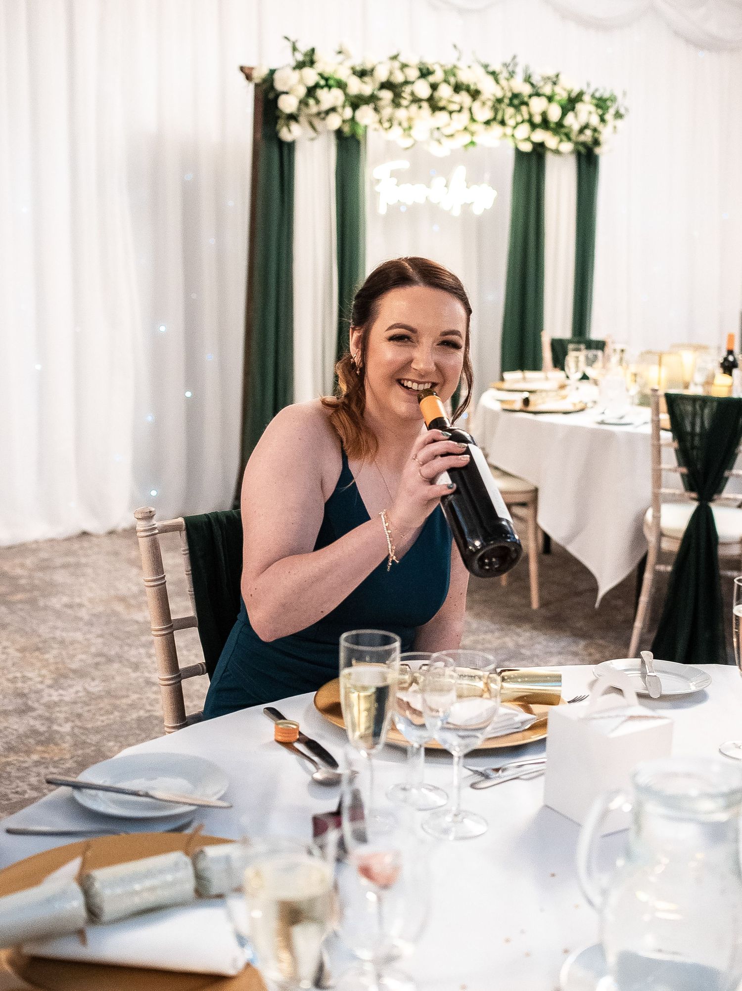 Guest enjoying drinks at elegant wedding reception with floral arch decor in background.