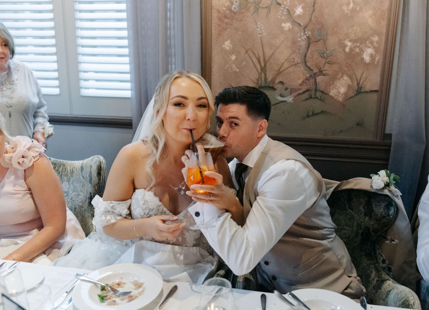 Wedding breakfast scene with elegant table settings and floral wallpaper.