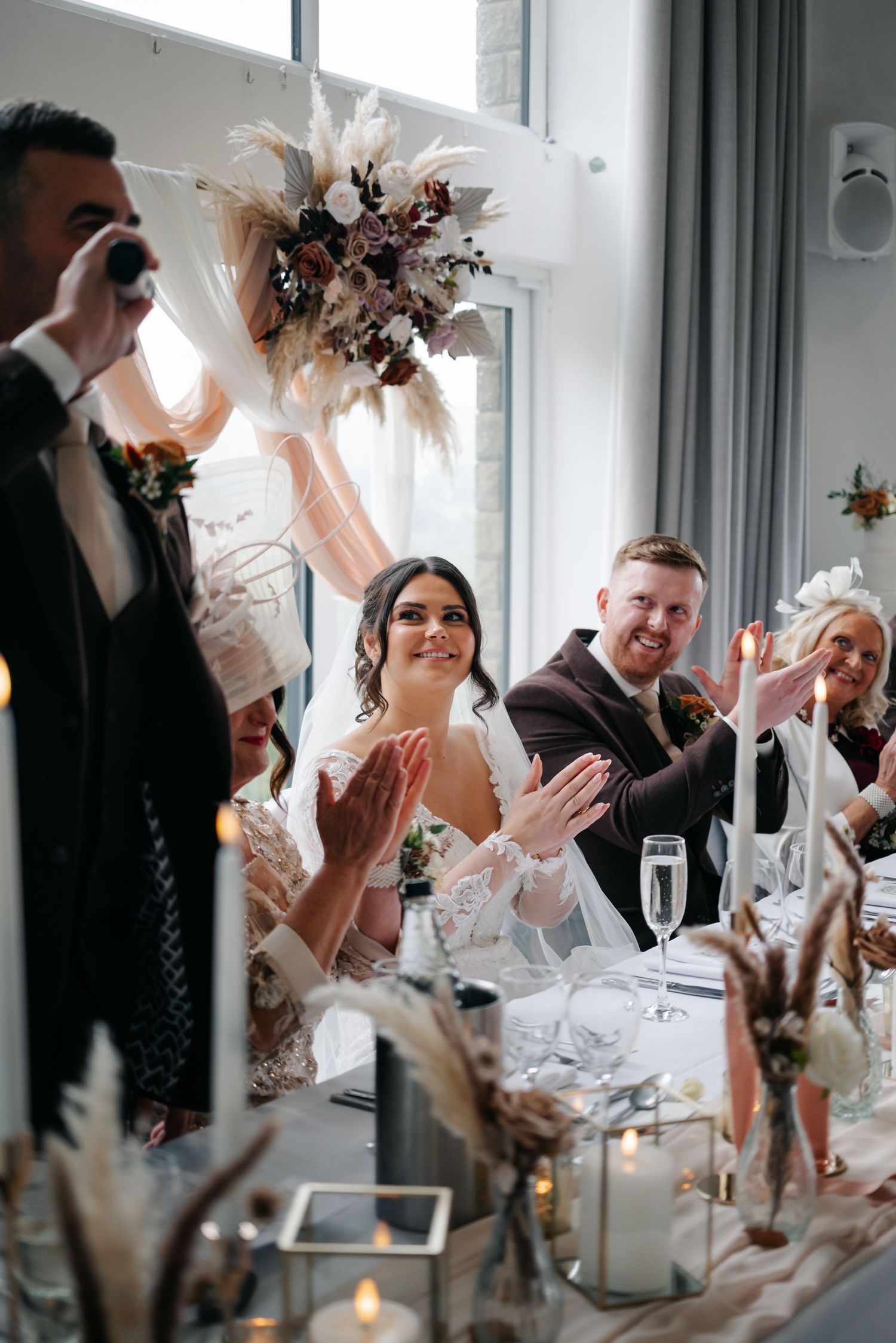 Wedding reception table setting with dried floral arrangements and candlelight creating an intimate atmosphere.