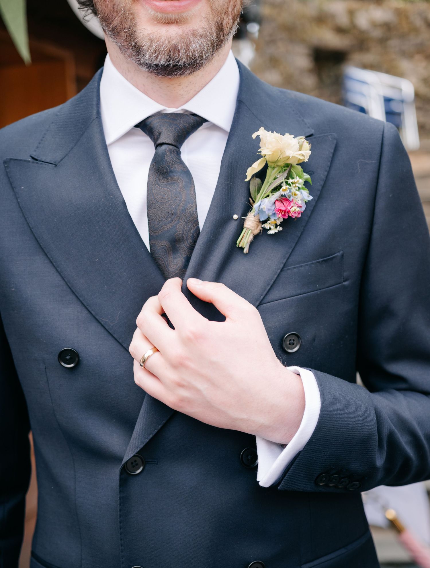 Close-up details of groomsmen's black suits with small floral boutonnieres.