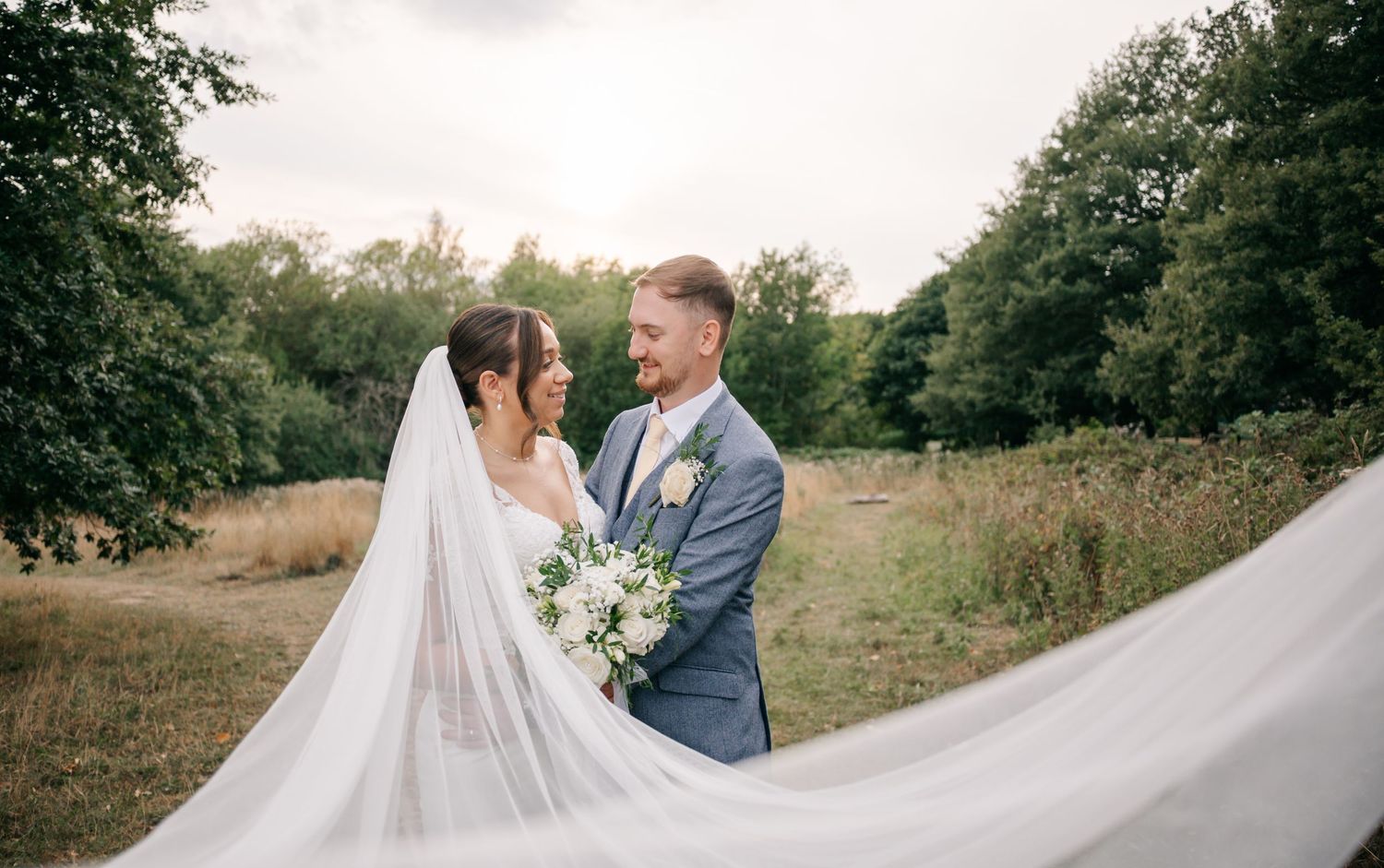 Wedding dress train flowing dramatically across a rustic outdoor setting.