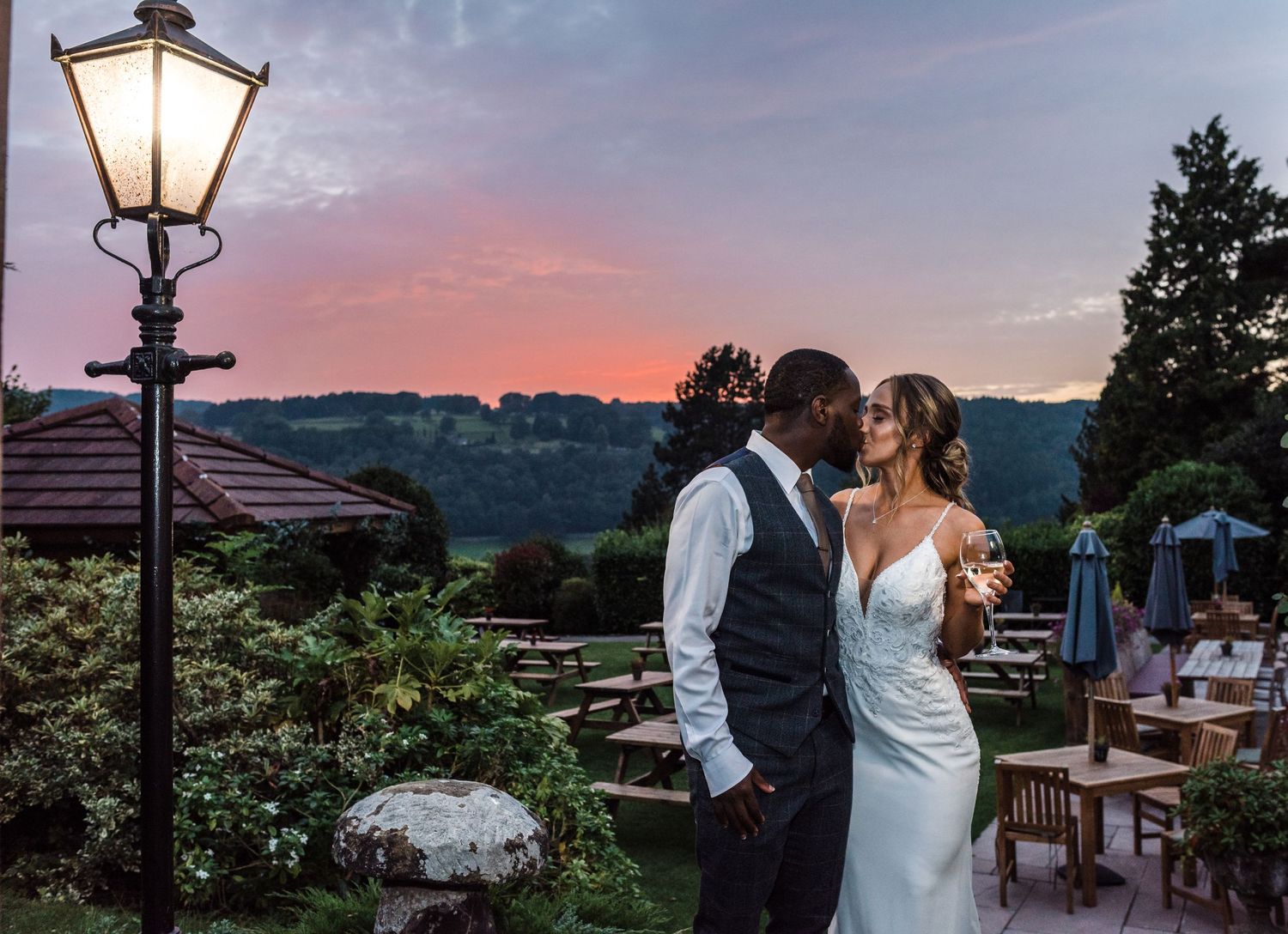 Romantic sunset silhouette of couple embracing on outdoor terrace with vintage lamppost.
