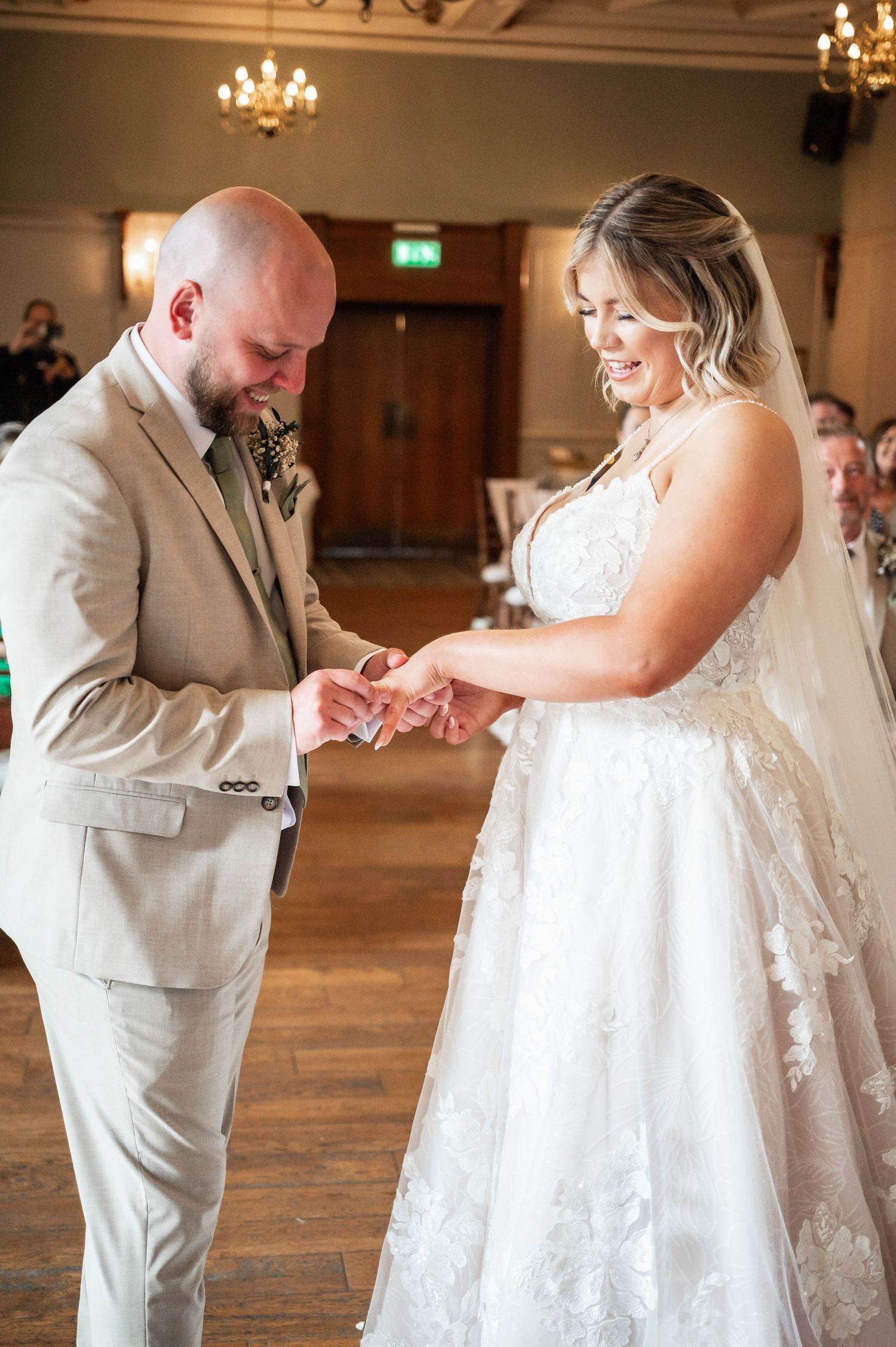 Exchange of rings during indoor wedding ceremony with hardwood floors.