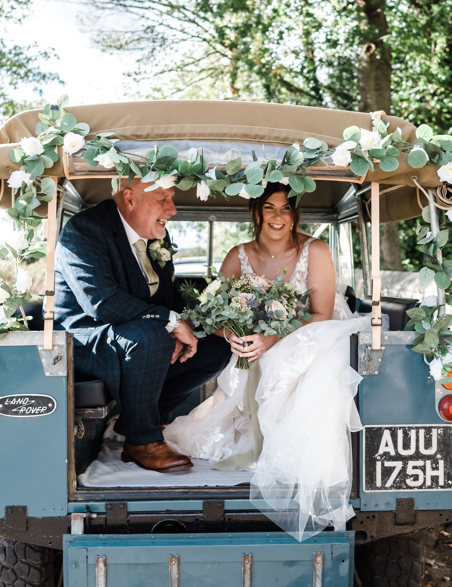 Couple riding in a vintage decorated tractor with eucalyptus garlands.