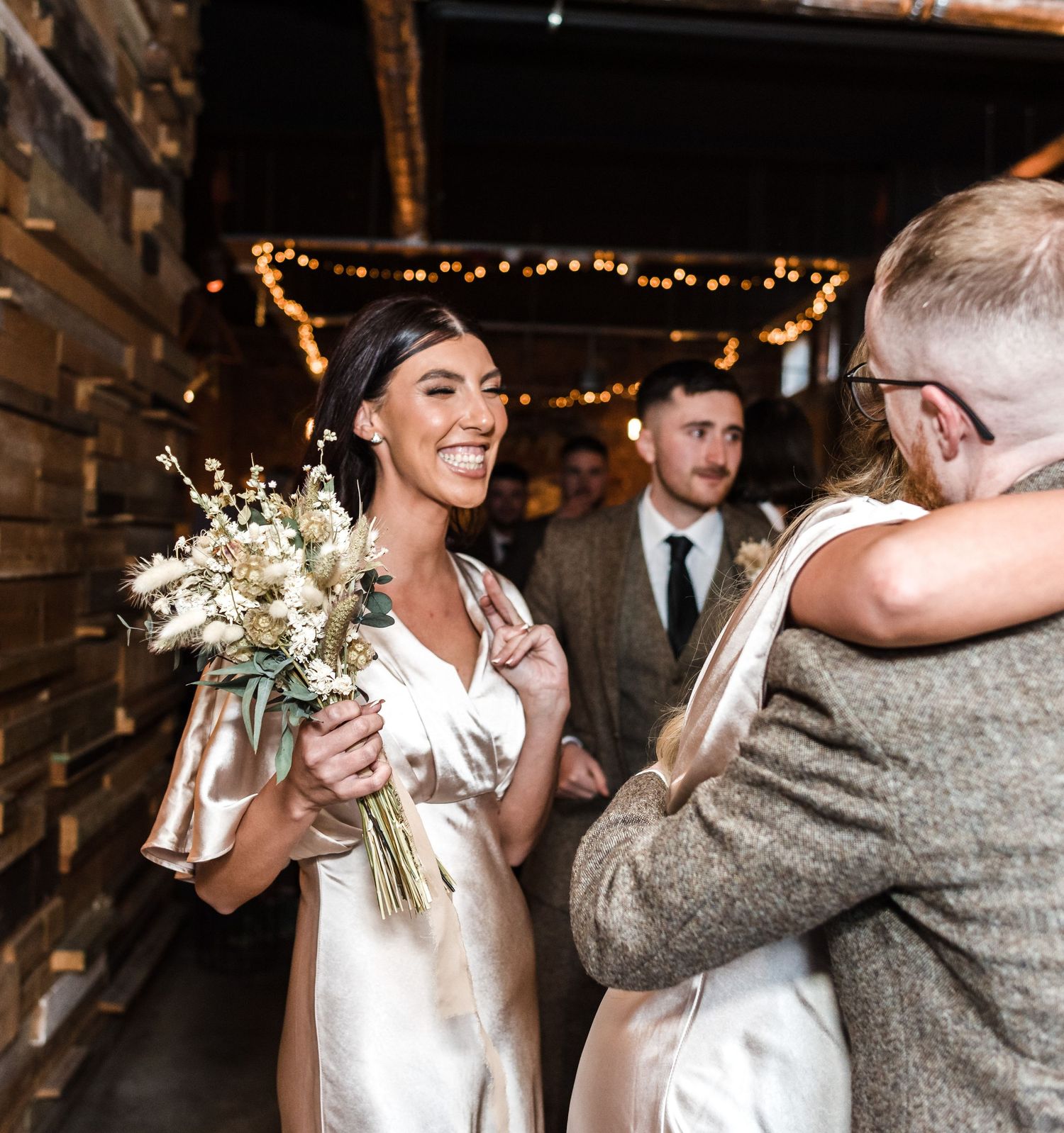 Wedding party member holding delicate white floral bouquet in rustic venue setting.
