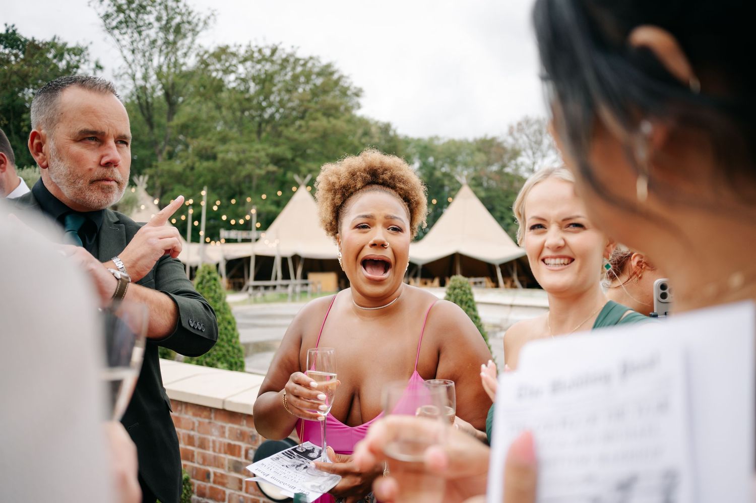 Wedding guests laughing and celebrating outdoors.