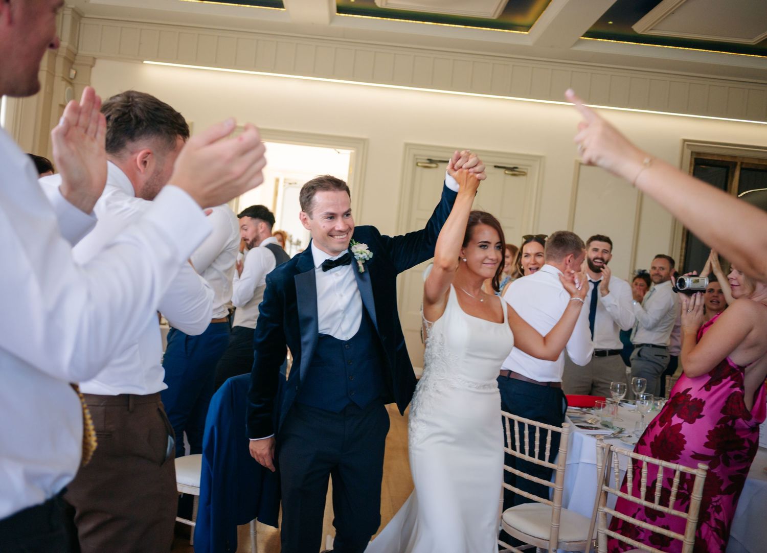 Wedding reception dance floor filled with celebrating guests and raised hands.