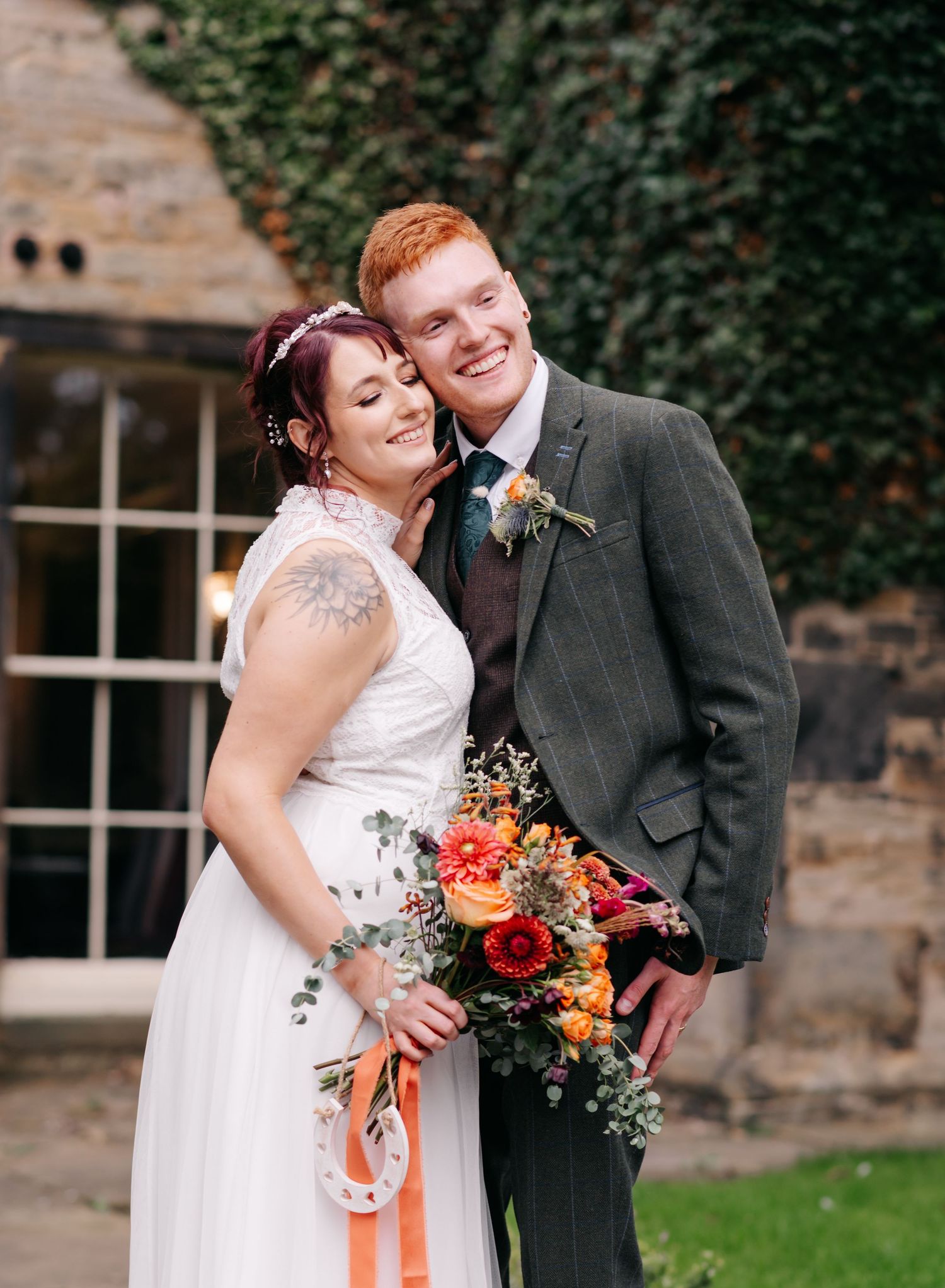 Romantic autumn wedding portrait against an ivy-covered stone wall.