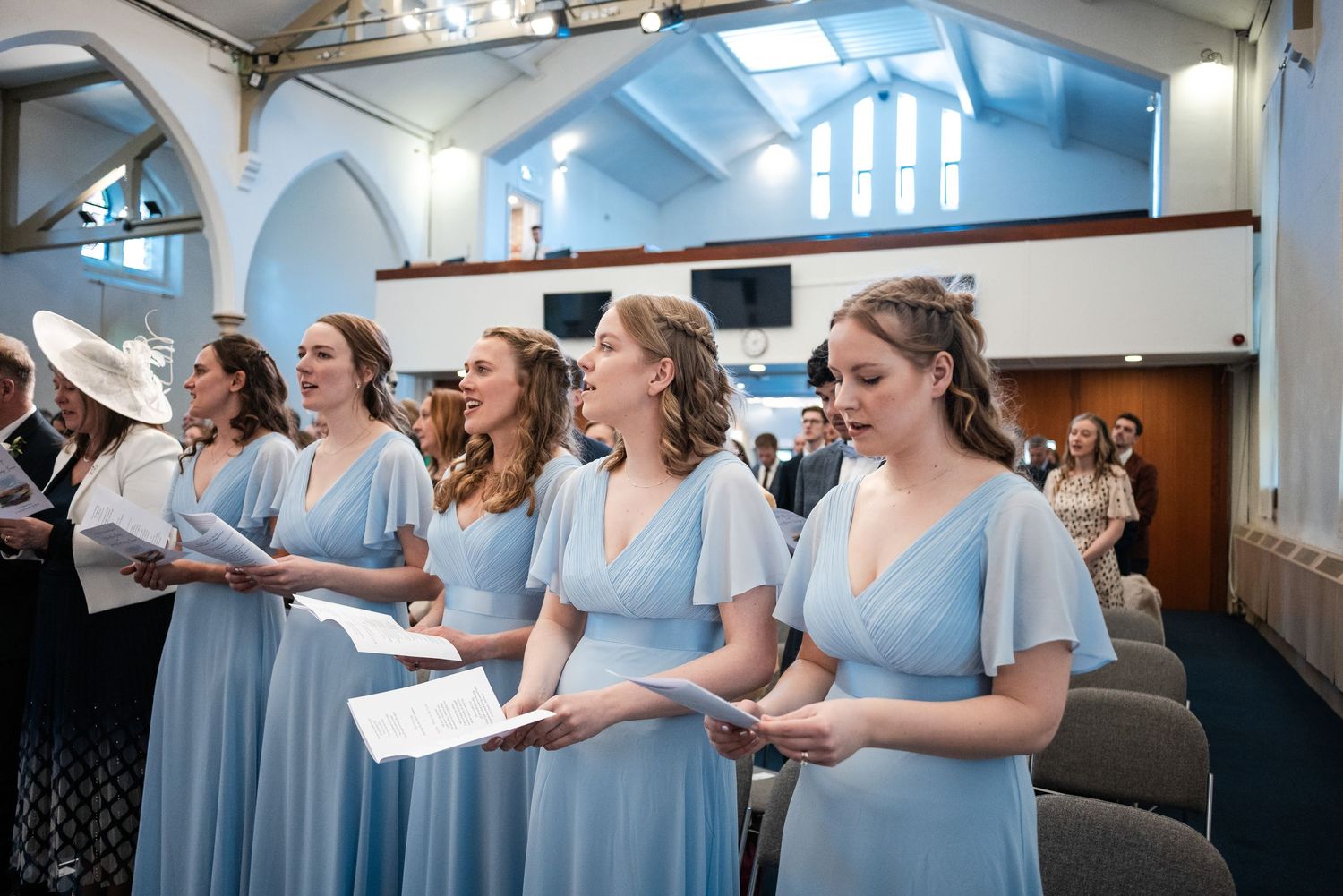 Bridesmaids in light blue dresses share joyful moments while getting ready for a wedding celebration.