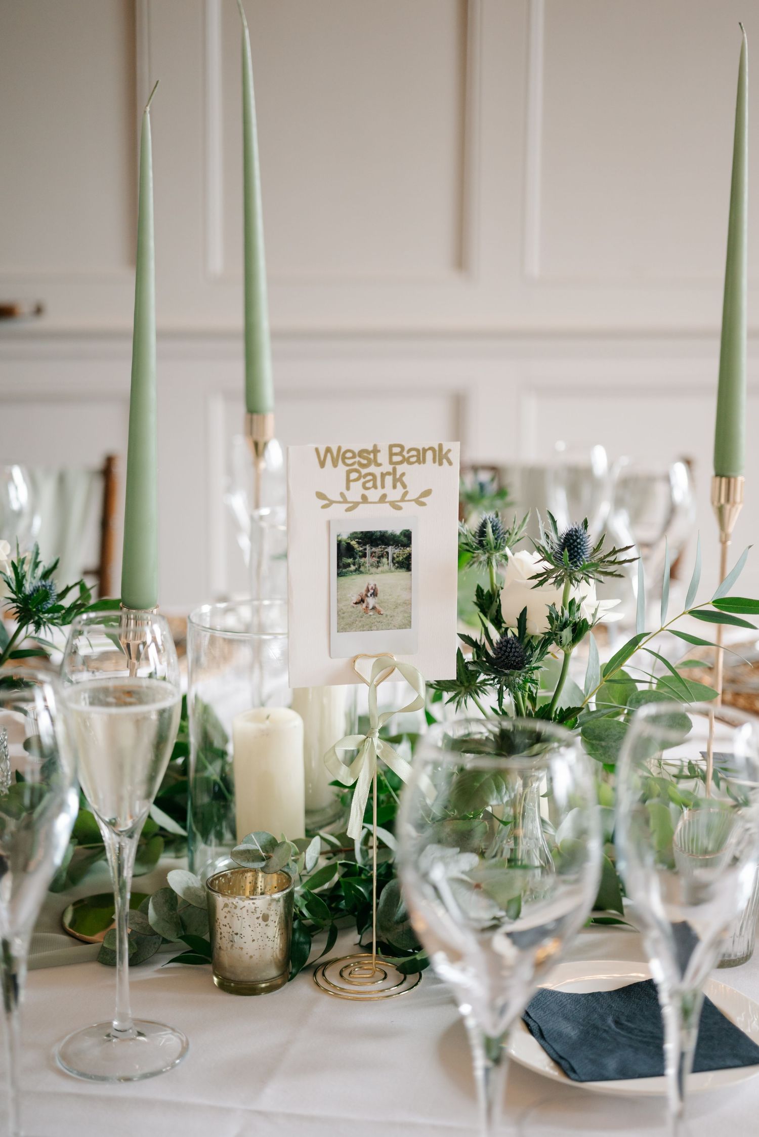 Elegant table setting with mint green candles, glassware and natural greenery centerpieces at West Bank Park.