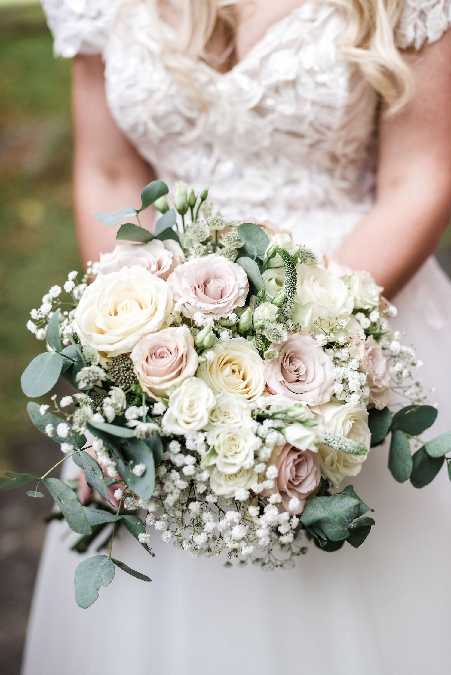 Close-up of romantic bridal bouquet with blush roses, white flowers, and eucalyptus leaves.