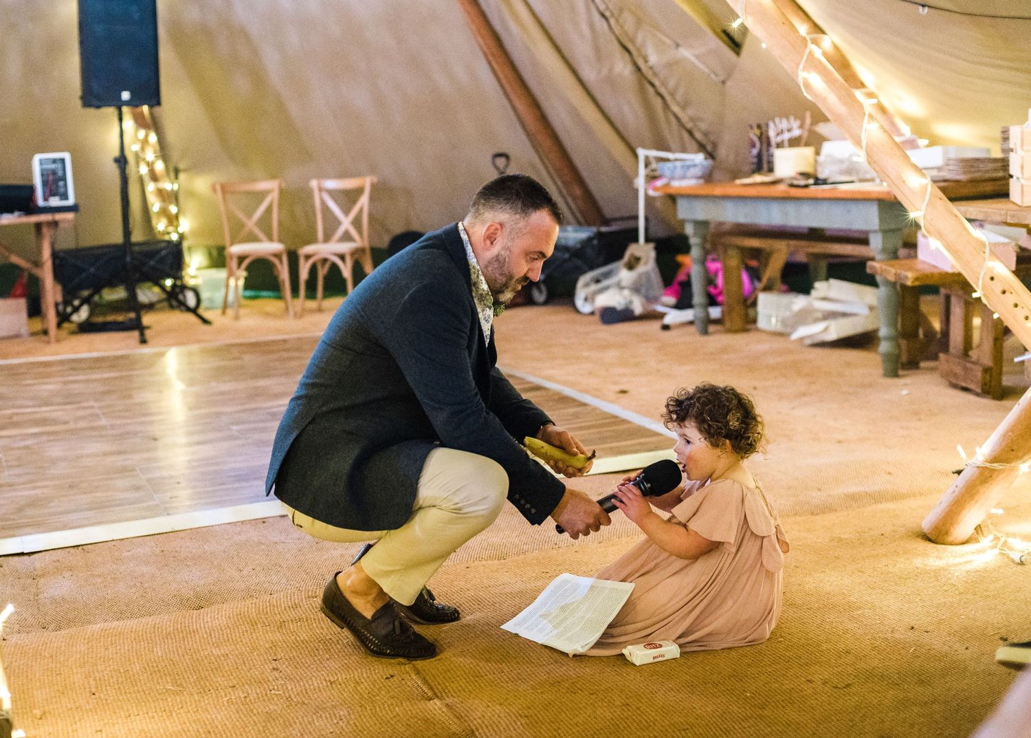 Sweet moment of dancing between child and adult in formal wear inside a tent reception.