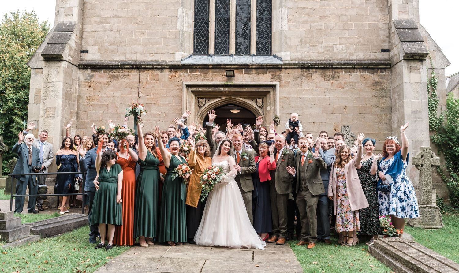 Large group wedding photo of guests and couple on church steps.