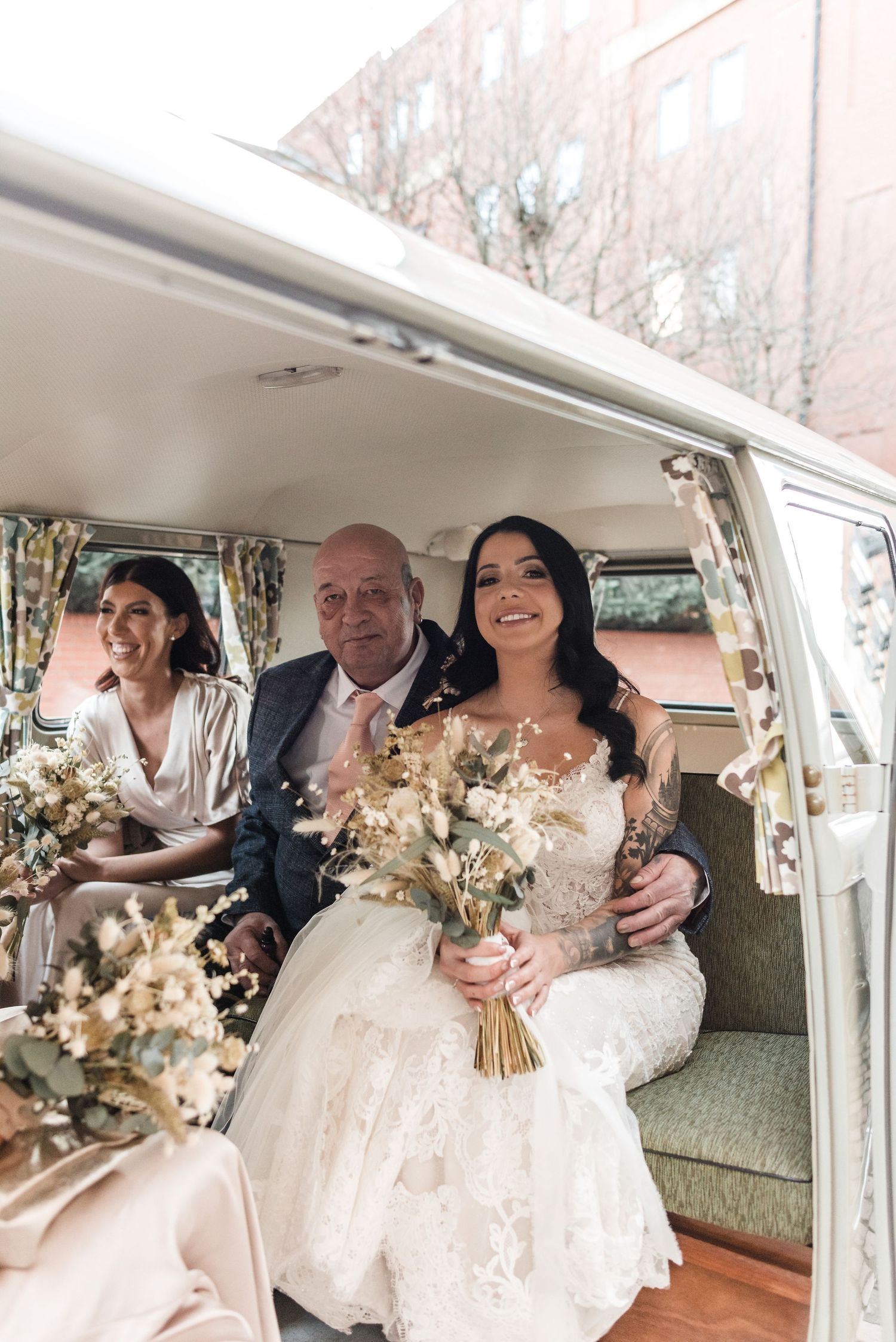 A bridal party sits inside vintage Volkswagen van with bouquets of dried flowers.