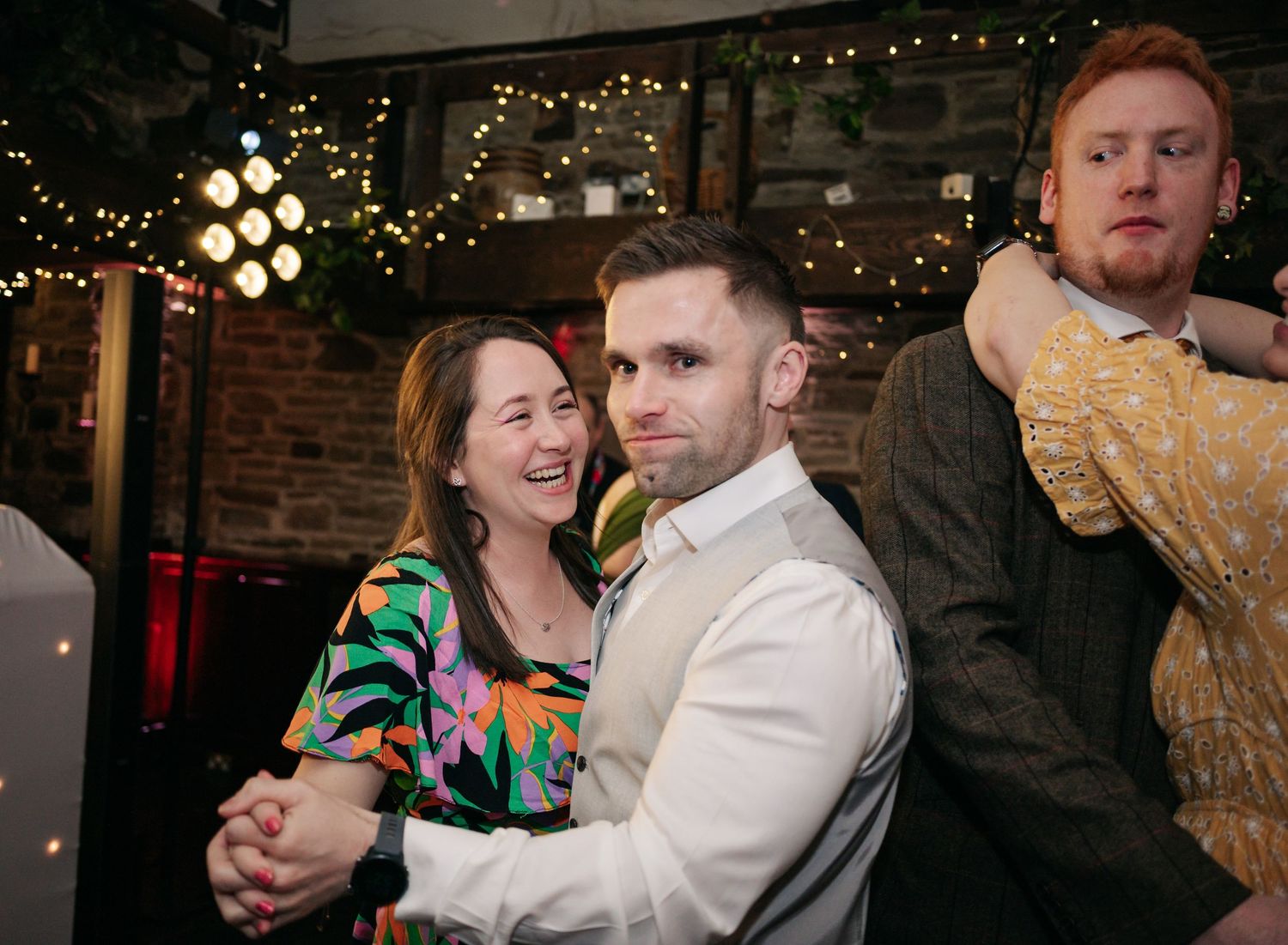 Wedding reception celebration with guests dancing and enjoying the festivities under string lights.
