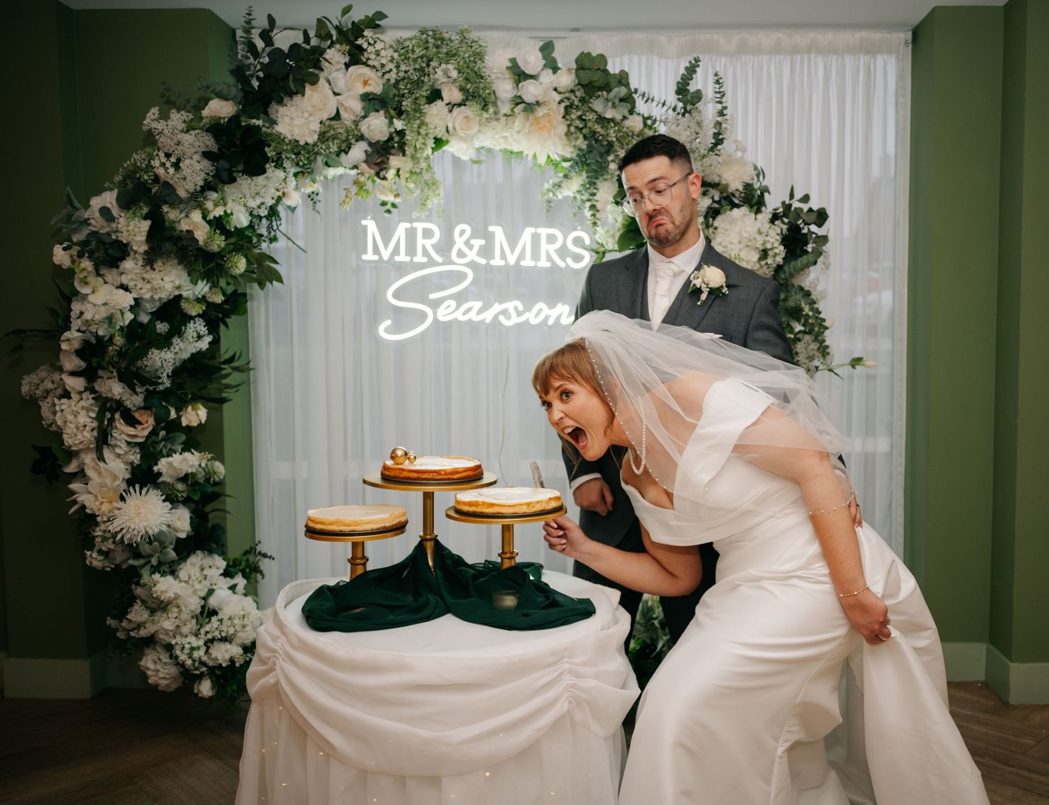 Wedding venue decorated with white floral arrangements and illuminated Mr & Mrs sign.