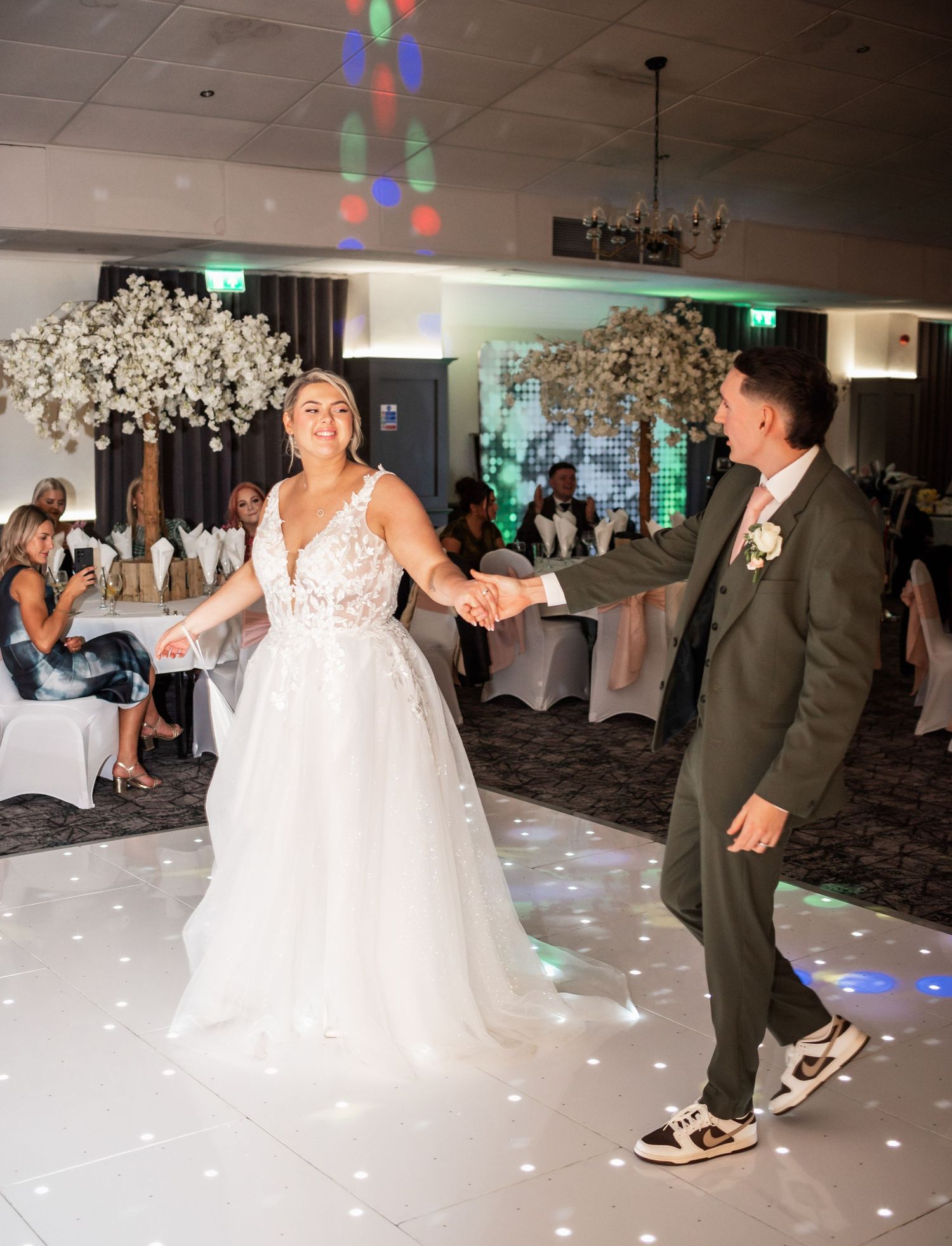 Couple dancing on illuminated dance floor during wedding reception.
