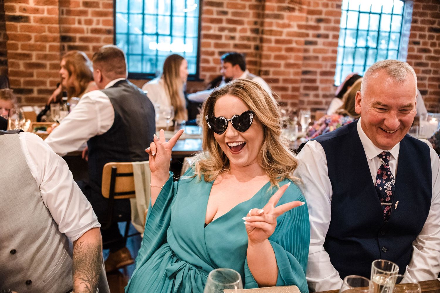 Wedding reception guest enjoying celebration in industrial-style venue with brick walls.