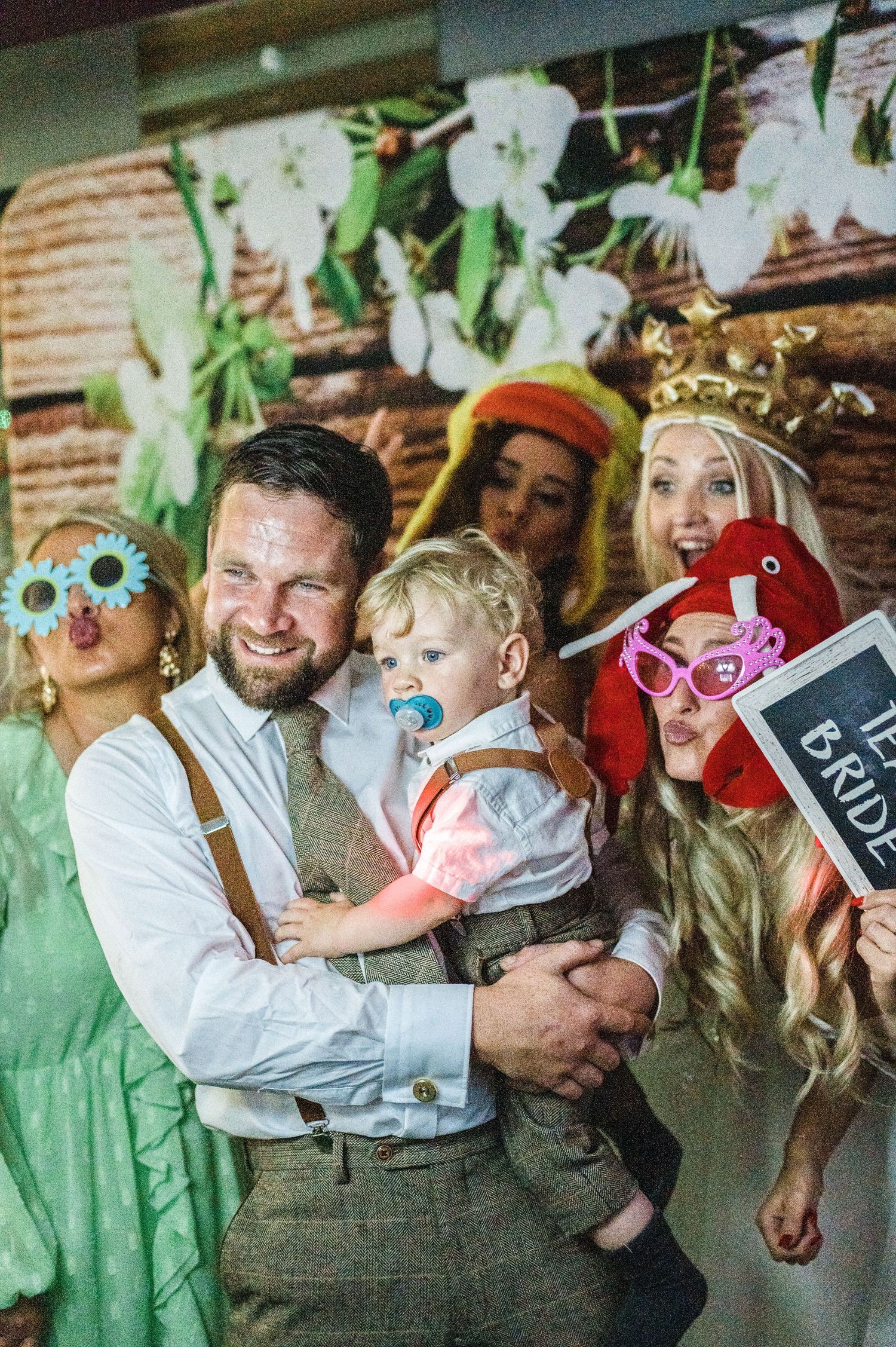A fun photo booth moment at a wedding with guests wearing colorful novelty glasses and props.