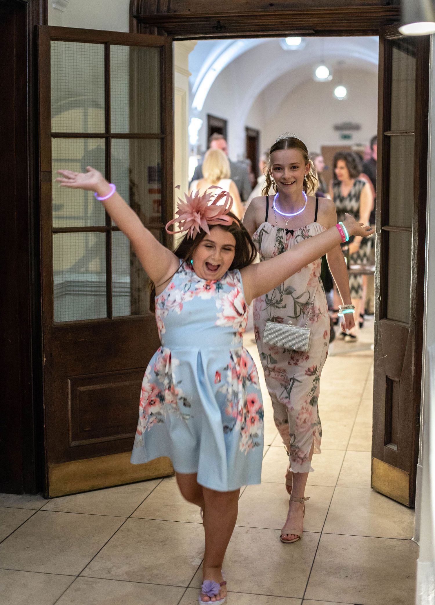 Young wedding guests dance and celebrate while entering through wooden doors.