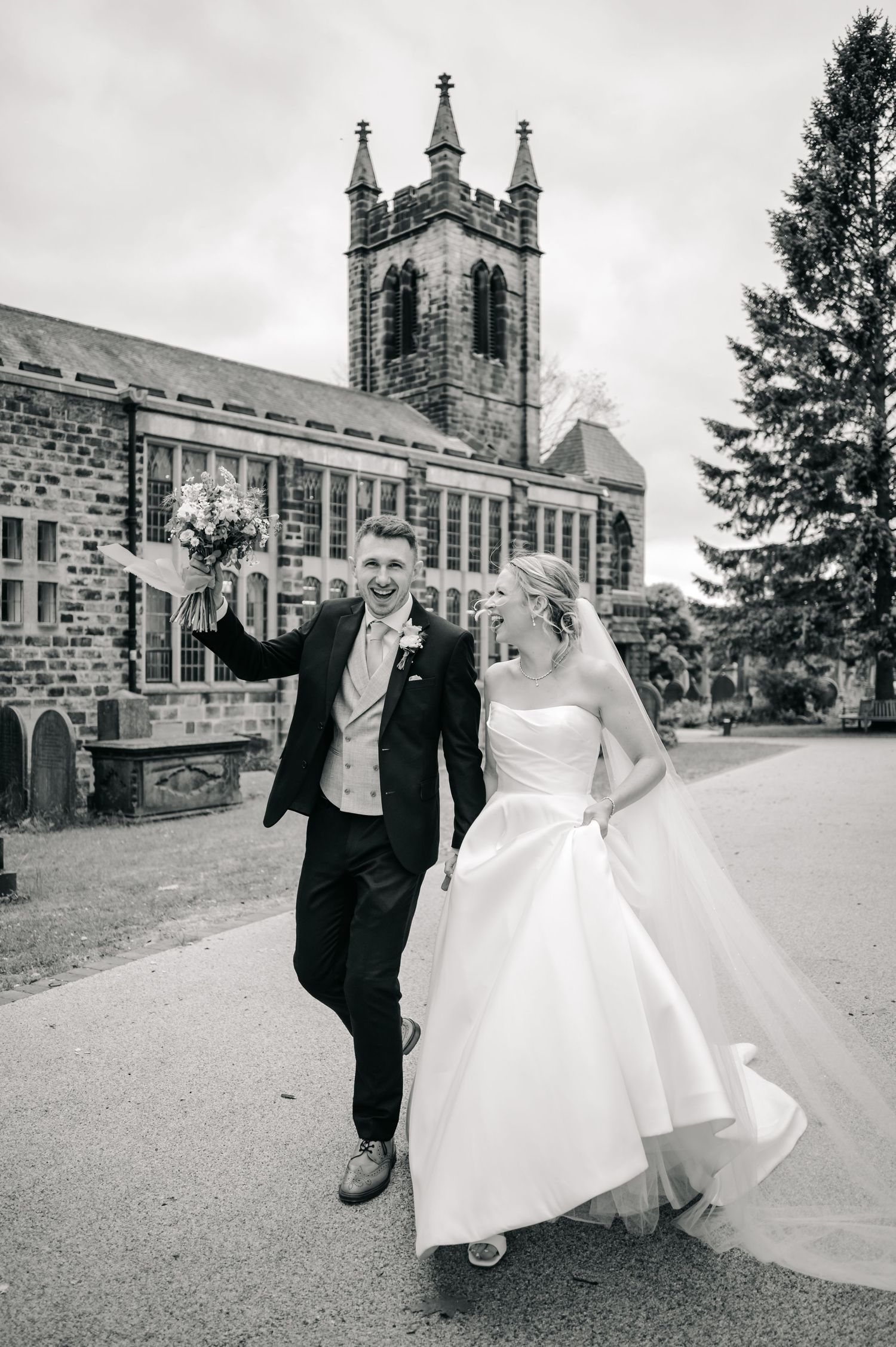 Black and white wedding portraits captured outside grand stone church building.