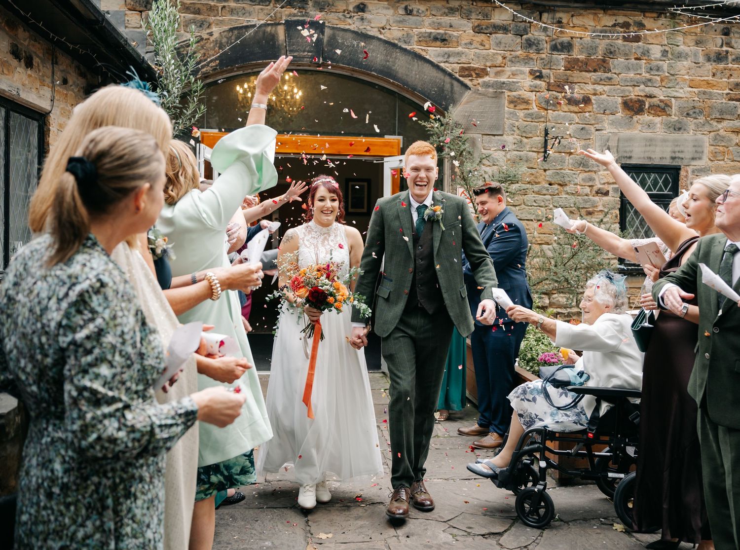 Wedding guests mingling and taking photos at an outdoor stone venue.