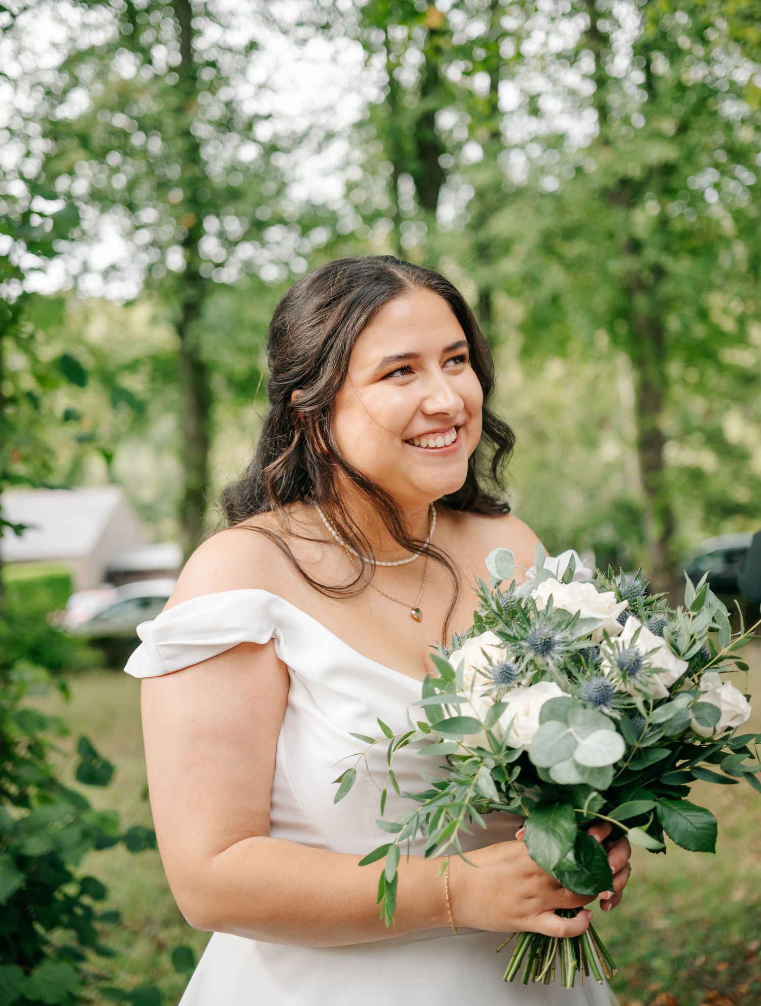 White bridal bouquet with eucalyptus and roses in an outdoor garden setting.
