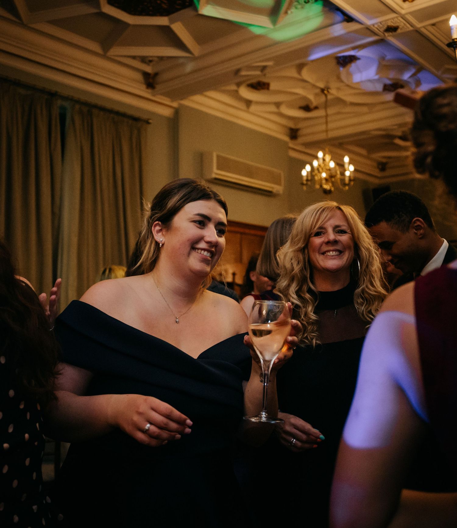 Wedding guests enjoying themselves on a dimly lit dance floor with colored lighting effects.