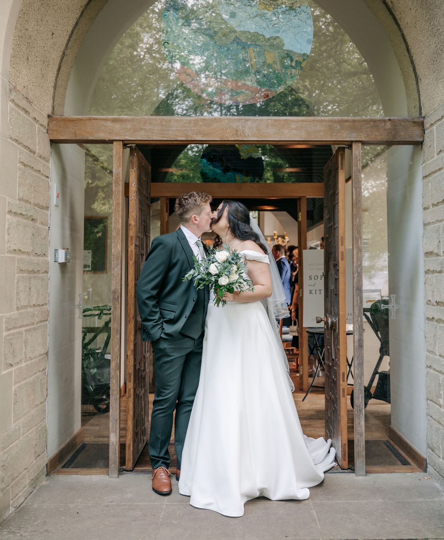 Wedding couple exiting through stone archways of a church after their ceremony.