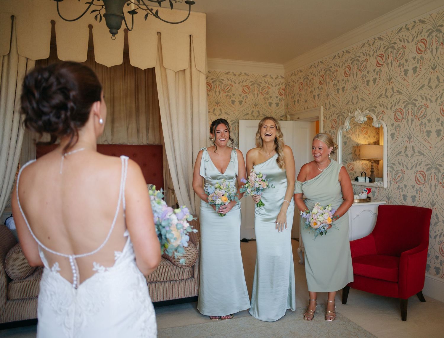 Bridesmaids in light blue dresses react with joy and excitement during a wedding day reveal moment.