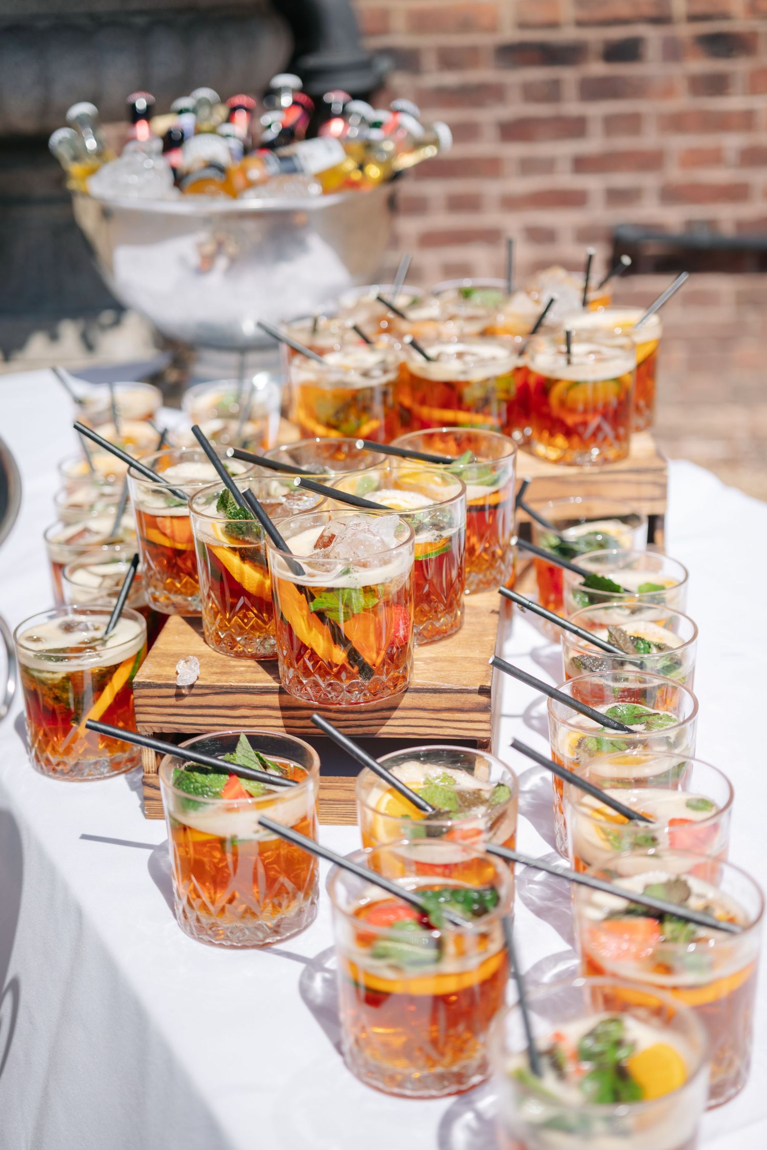 Crystal glasses filled with orange cocktails garnished with fresh herbs and citrus on a wooden serving board.