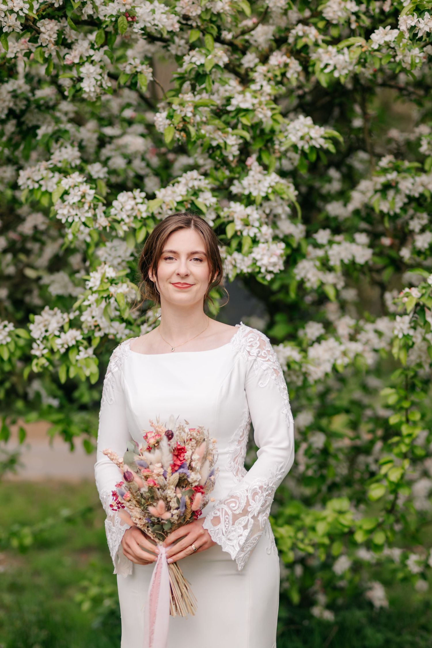 Spring wedding portrait with flowering tree blossoms and dried flower bouquet.