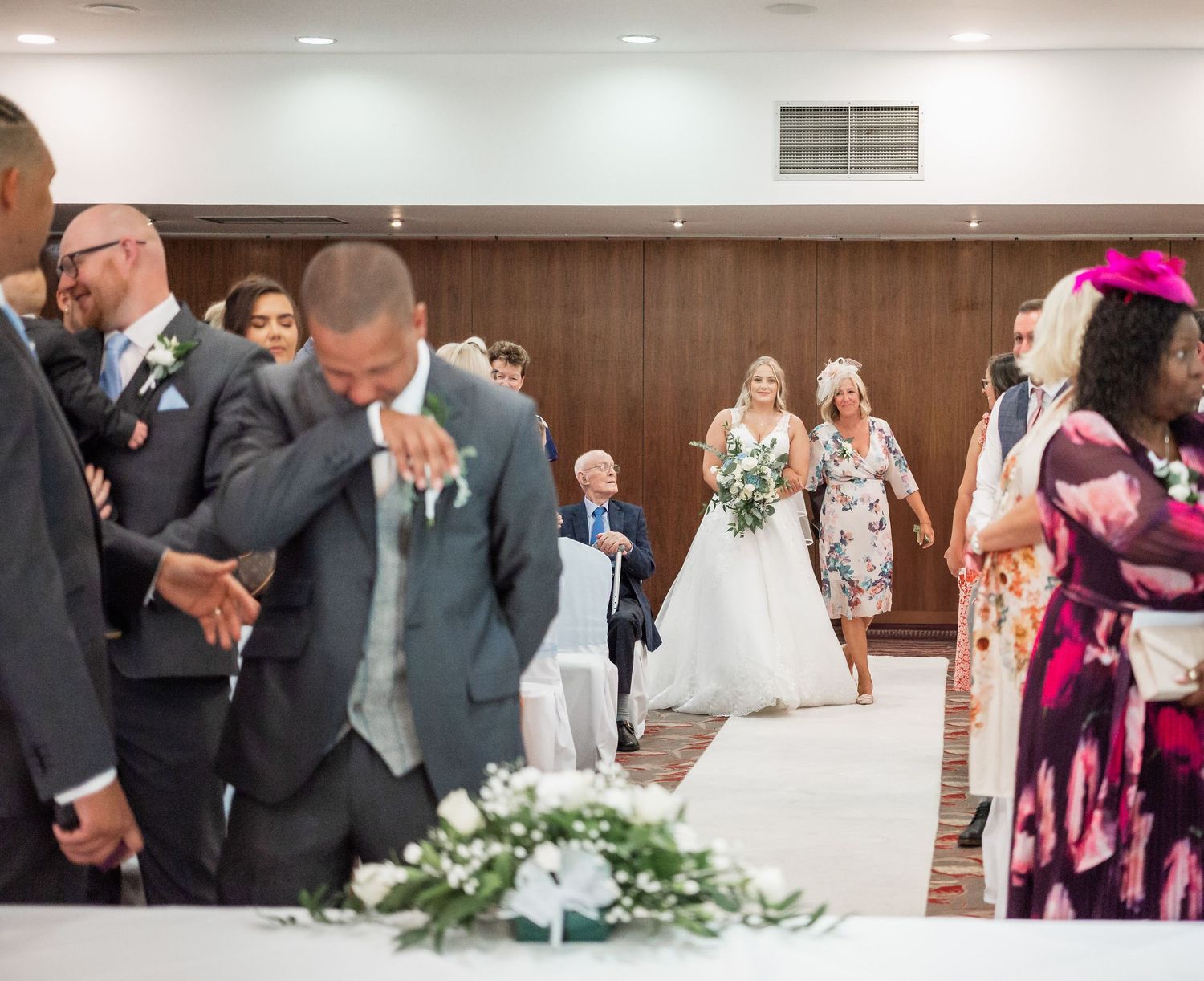 Wedding ceremony scene with floral decorations in an indoor venue.