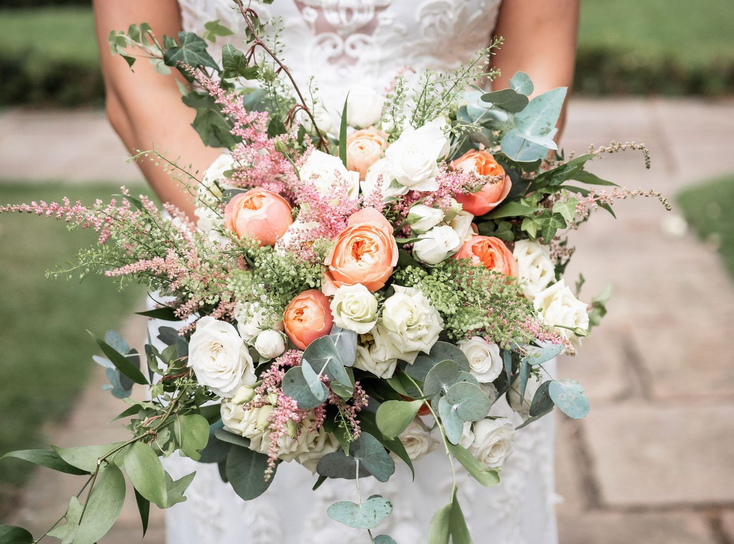 Elegant bridal bouquet featuring peach and white roses with eucalyptus and wildflower accents.