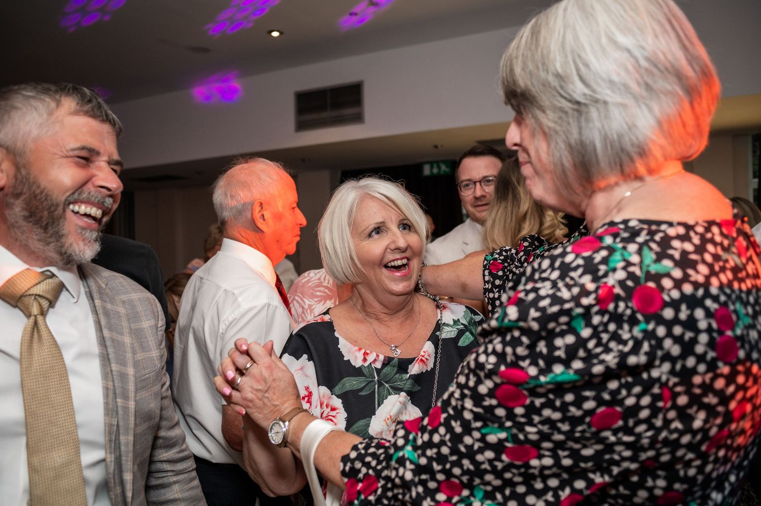 Wedding guests laughing and socializing during the reception celebration.
