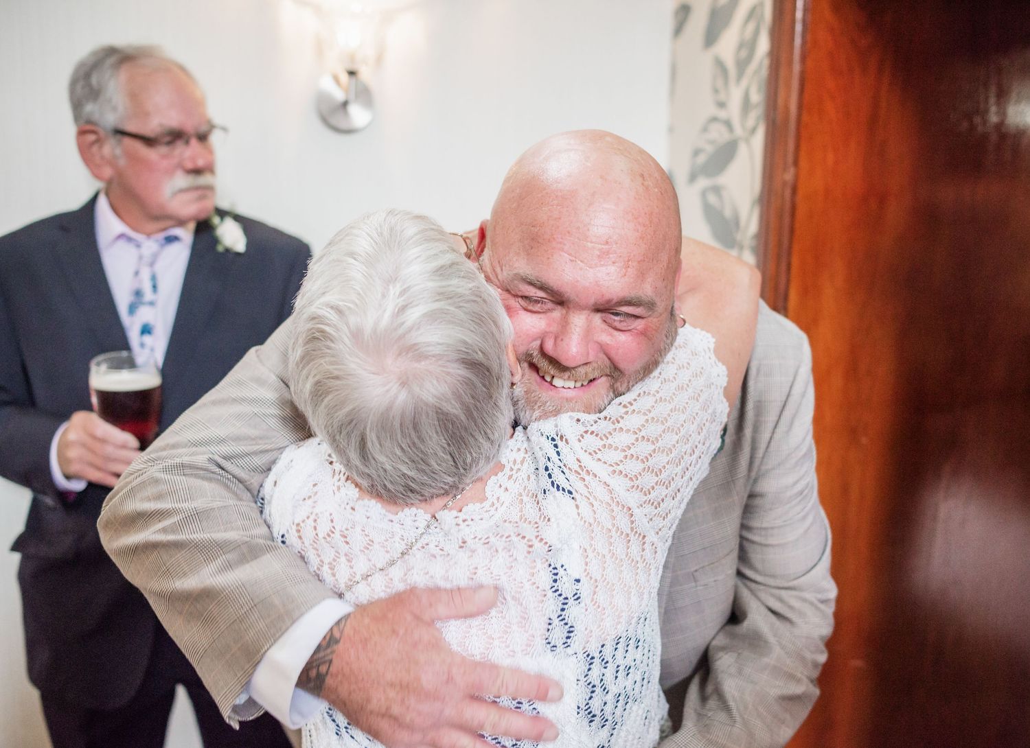 Emotional embrace at a wedding ceremony with guests looking on.