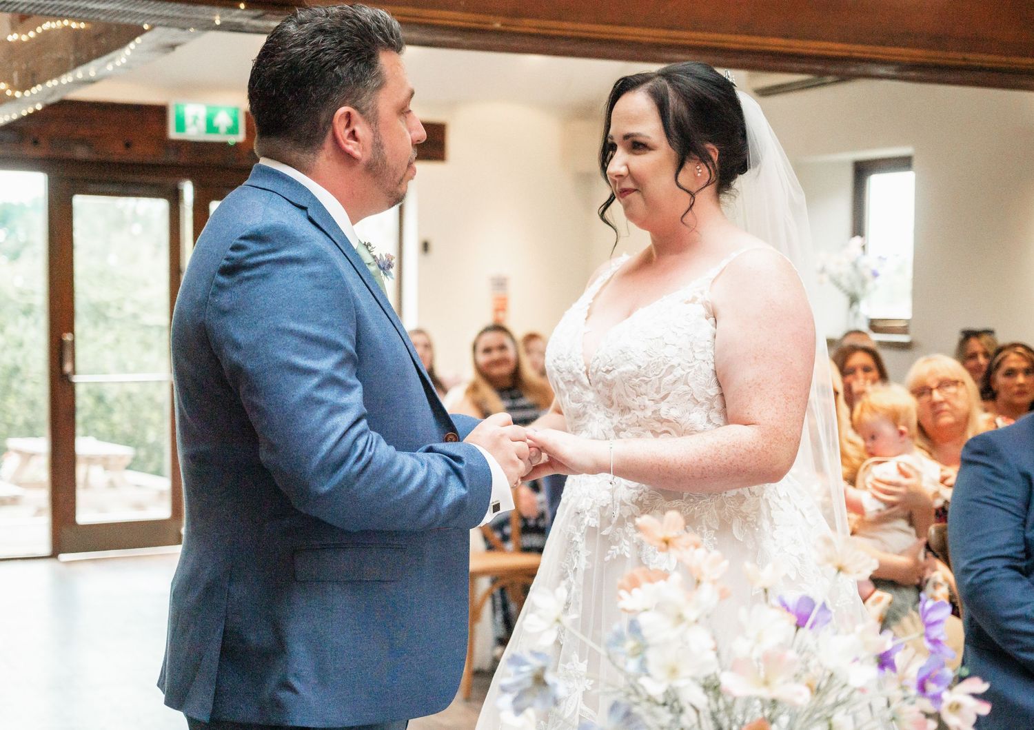 Wedding ceremony moment captured in venue with natural lighting and gathered guests.