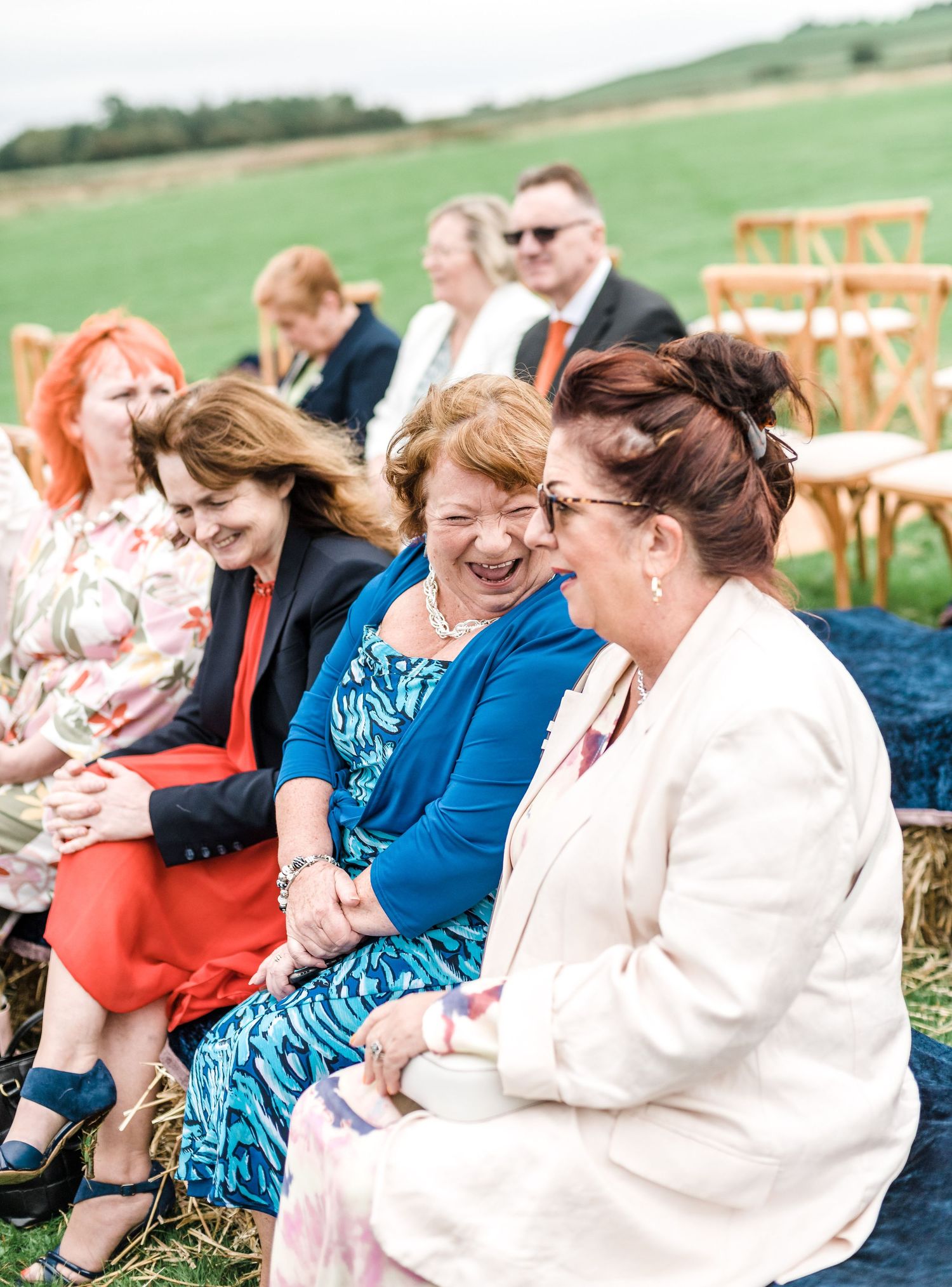 Wedding guests walking across lawn with tipi tents in background.
