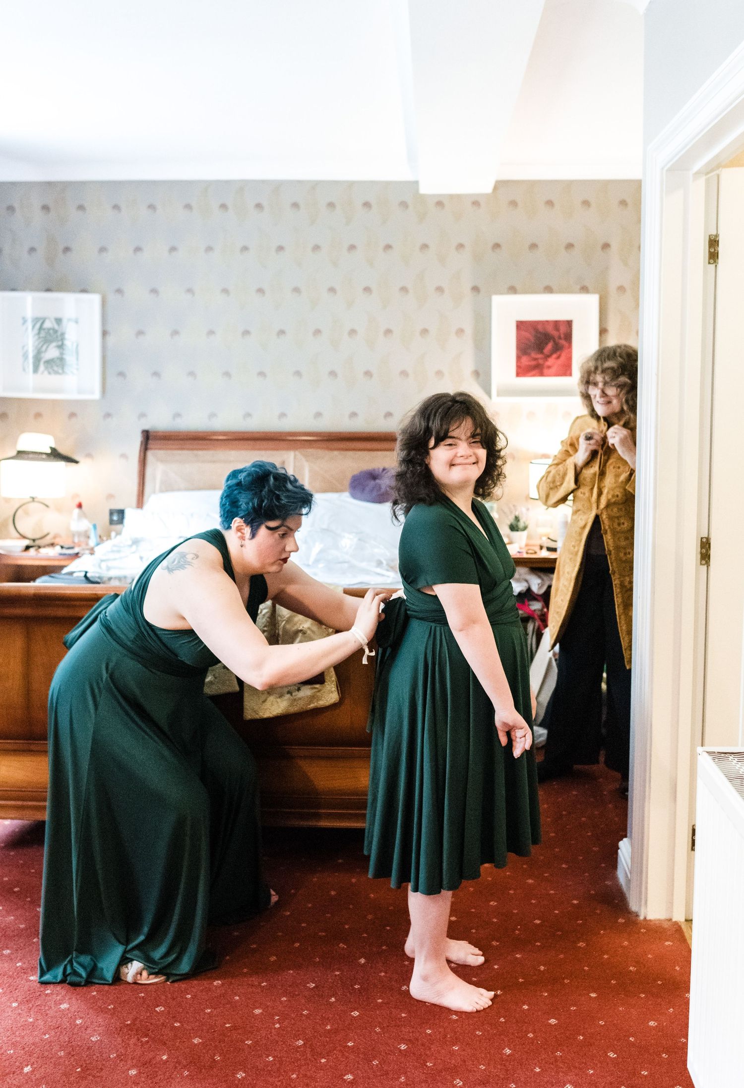 Wedding preparation scene with people in emerald green dresses getting ready in a hotel room.