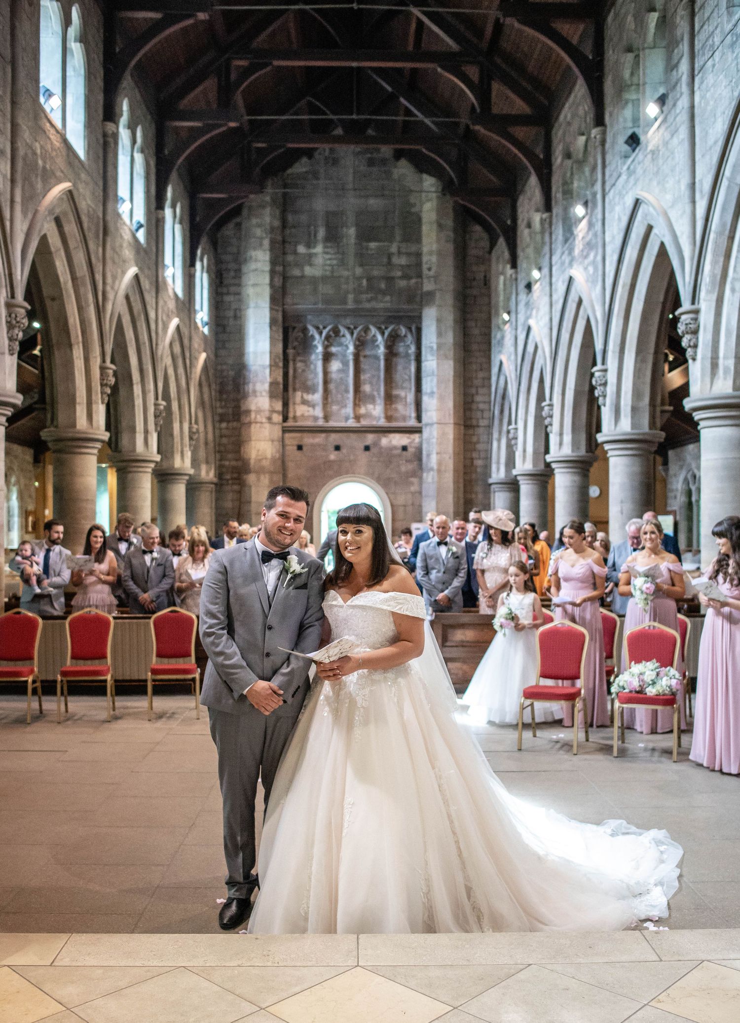 A wedding ceremony in a grand gothic church with stone arches and stained glass windows.