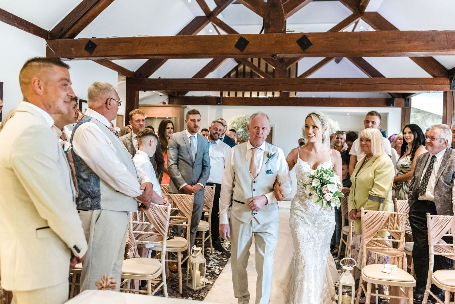 Wedding ceremony in rustic venue with exposed wooden beams and natural lighting.