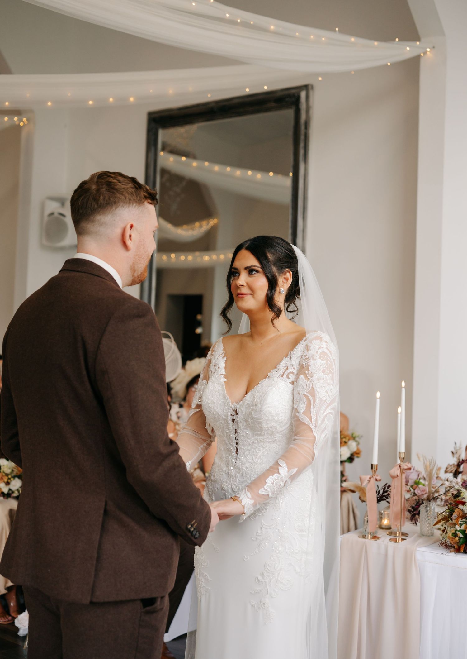 Wedding celebration in a light-filled venue with white draping and string lights overhead.