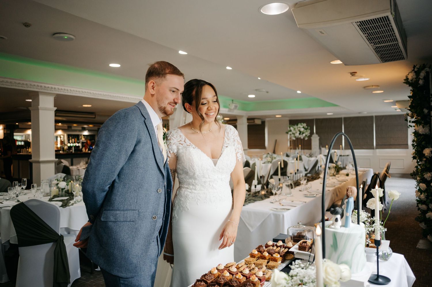 Elegant wedding reception setup with white tablecloths and place settings in a bright banquet room.