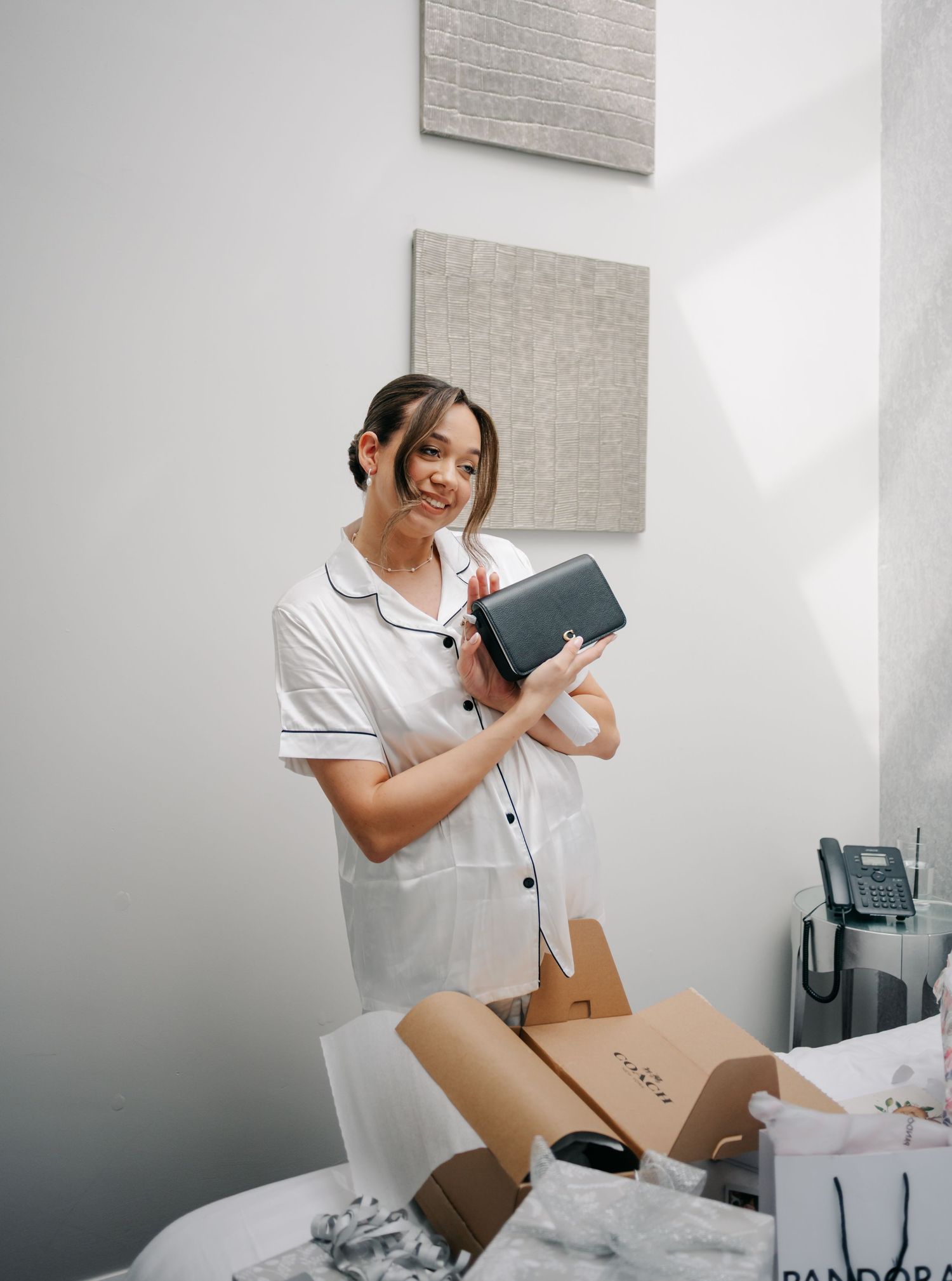 Person in white pajamas opening wedding day gifts and packages in a bright room.