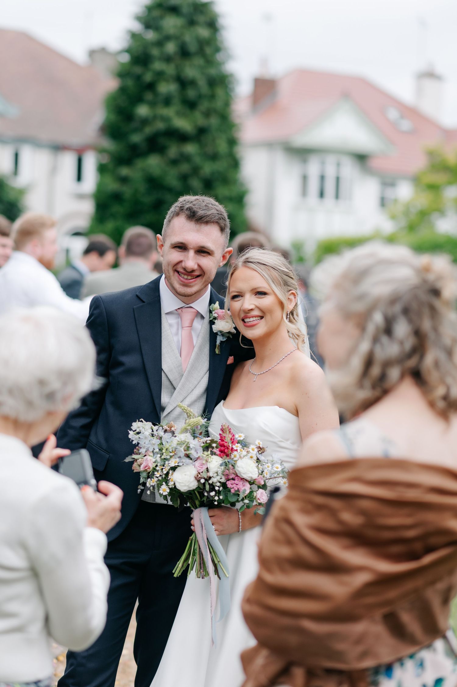 A couple shares a joyful moment at their outdoor wedding celebration, surrounded by guests.