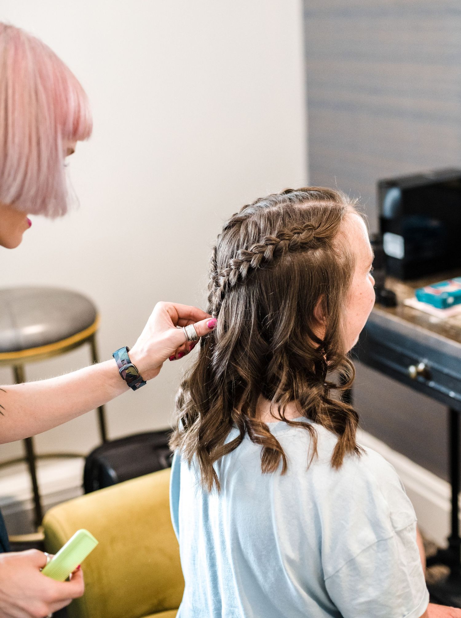 Hairstylist creating intricate braid hairstyle in salon setting.