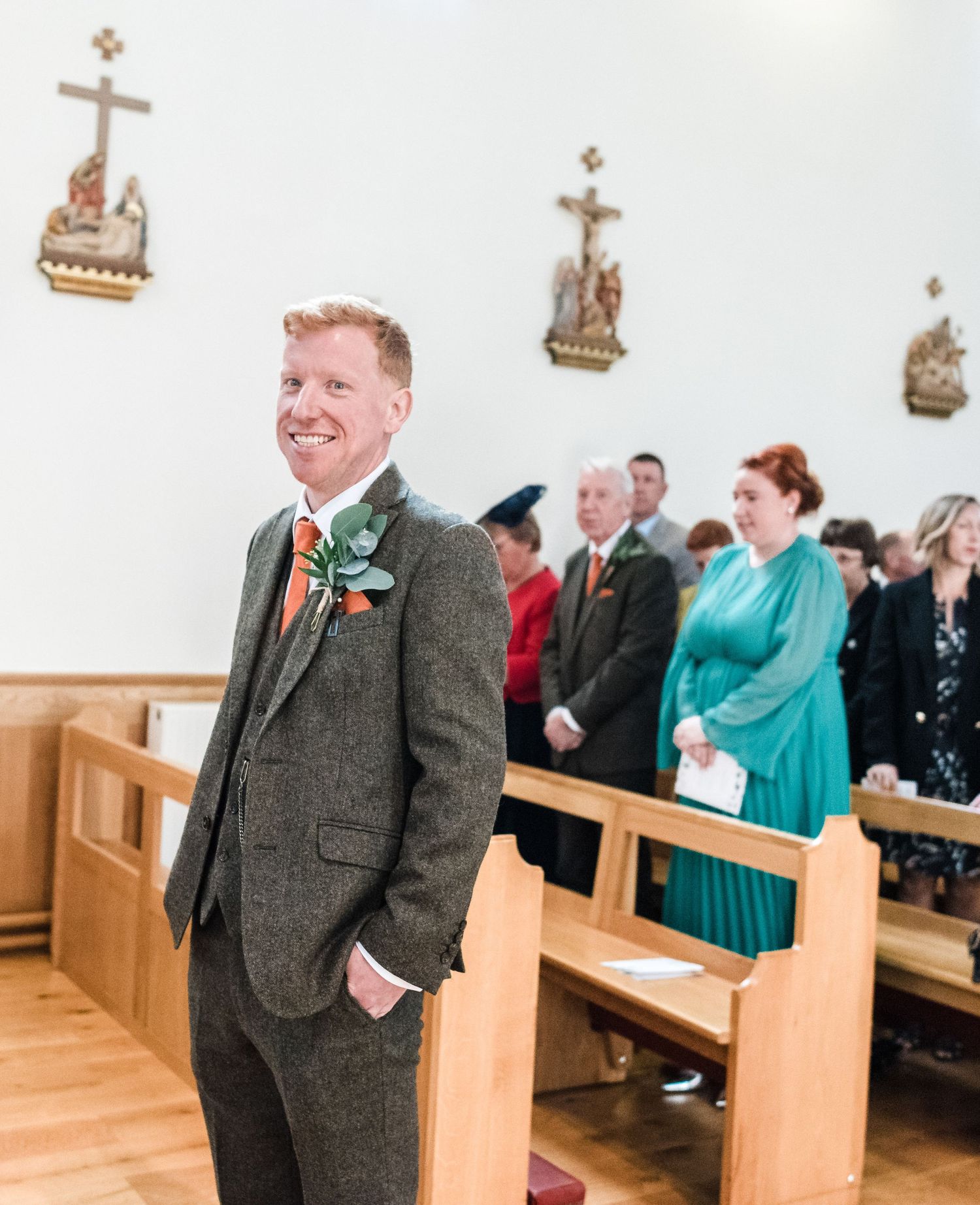 Wedding ceremony in a church with ornate crosses adorning white walls.