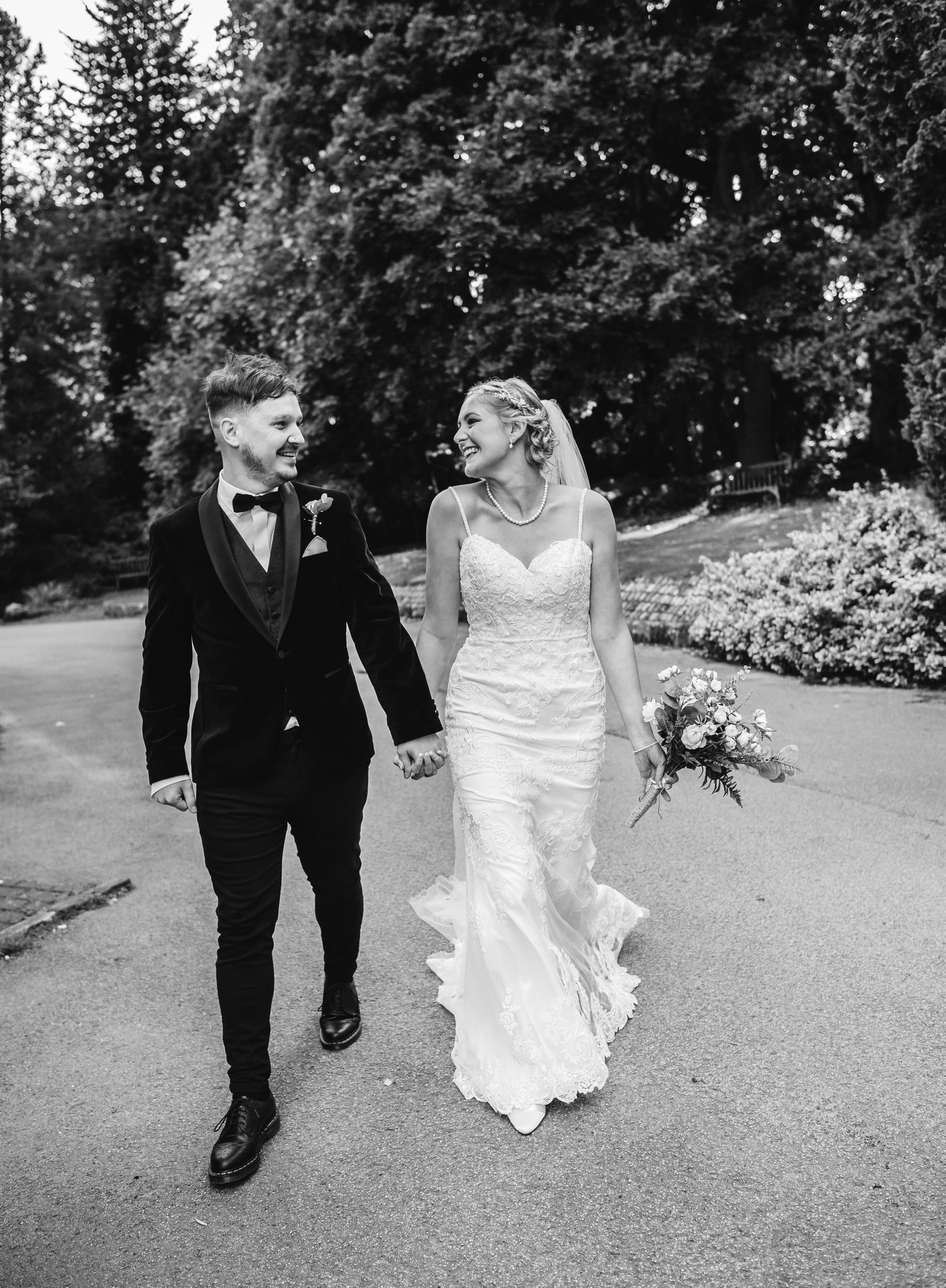 Black and white wedding photos of couple walking through scenic garden path.
