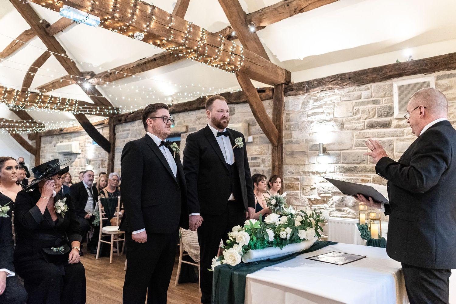 Wedding ceremony moment in a rustic barn venue with exposed beams and natural lighting.