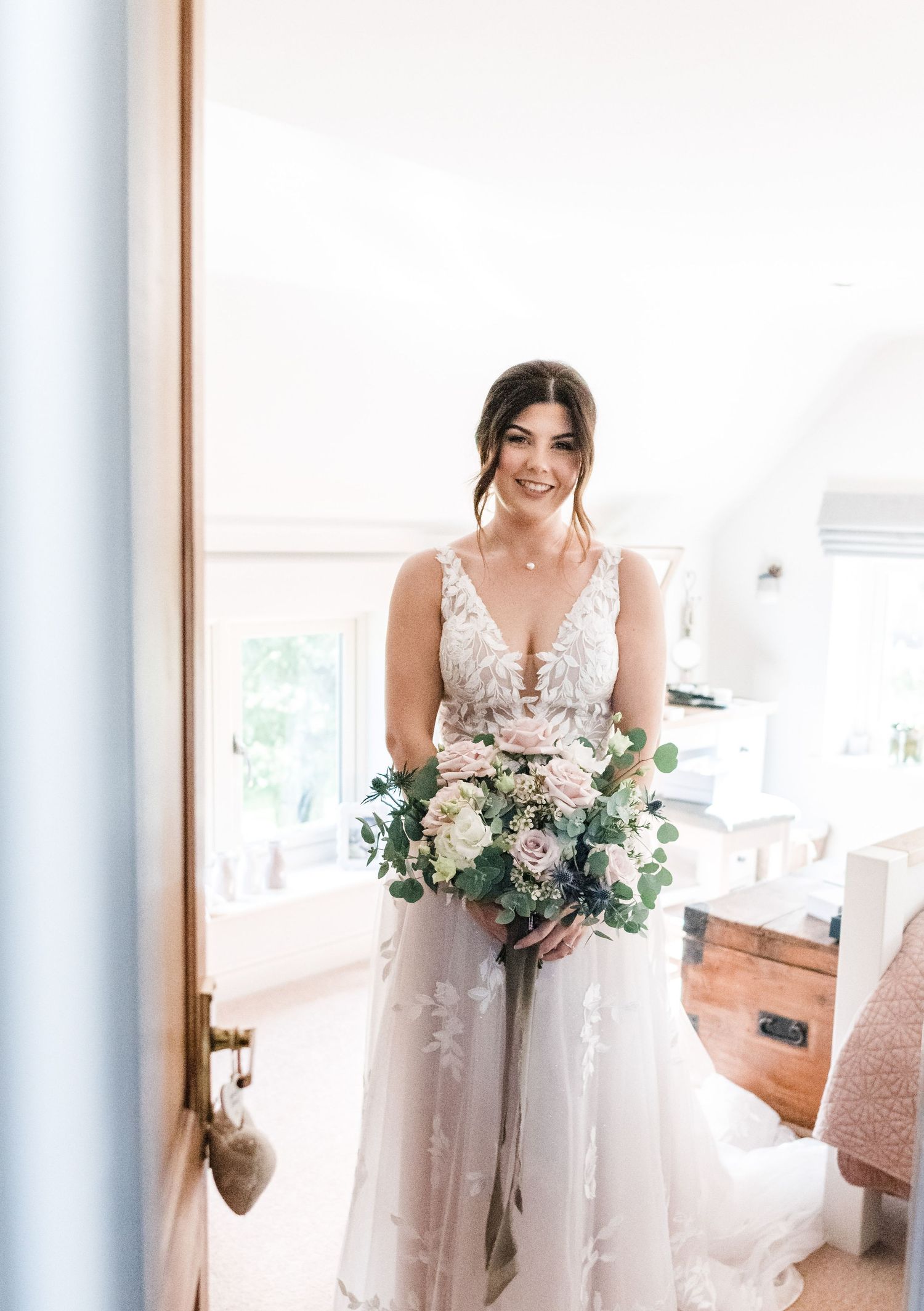 Elegant bridal portrait showing detailed lace wedding gown and romantic bouquet in natural light.